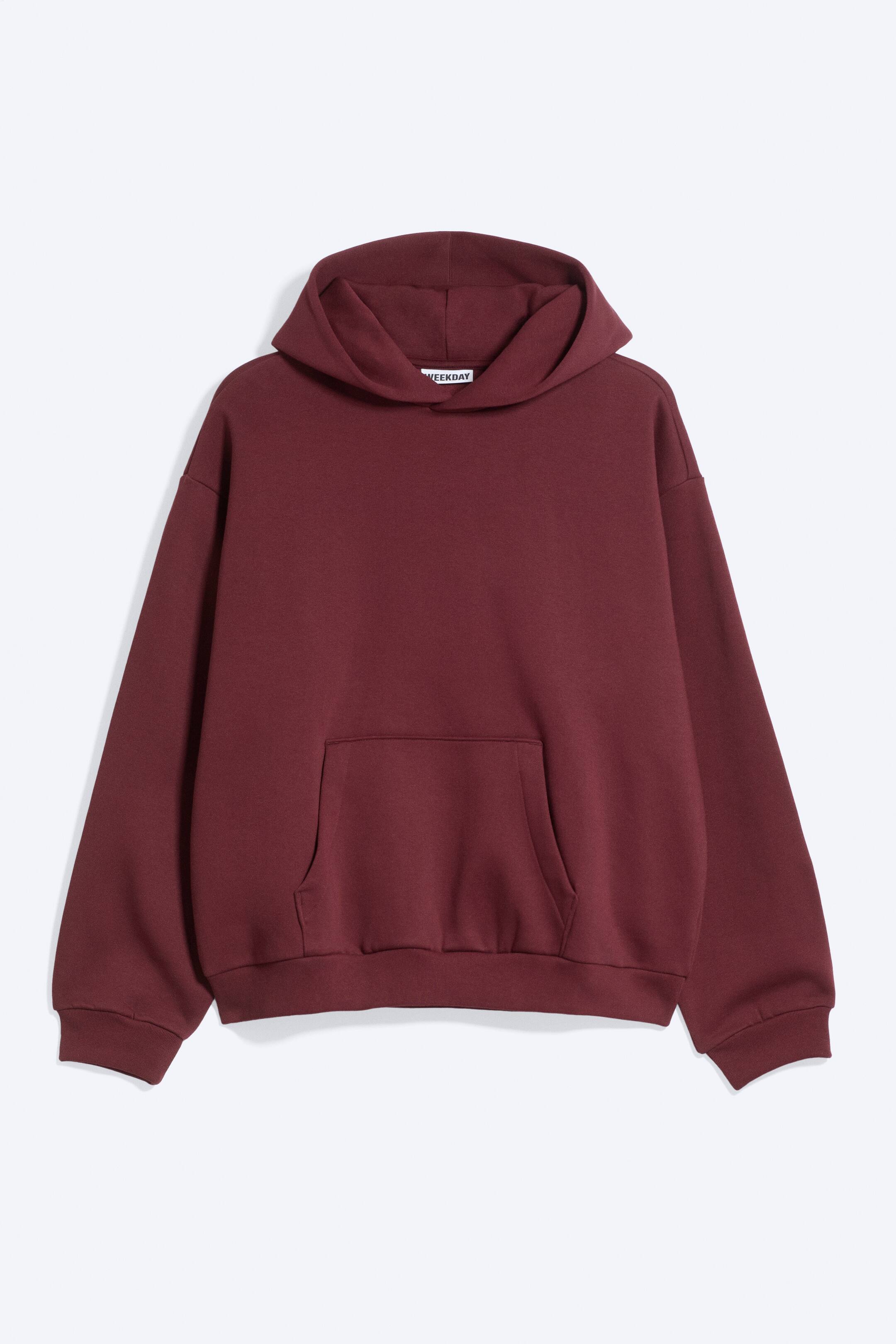 Größeres Bild anzeigen: Ein burgunderfarbener Fleece-Hoodie ist von vorne zu sehen und präsentiert eine lockere, weich strukturierte Passform mit überschnittenen Schultern, einer umgeschlagenen Kapuze und einer geräumigen Kängurutasche. Er verfügt über gerippte Bündchen und einen gerippten Saum mit dezenter Raffung, die eine entspannte, rundliche Silhouette erzeugt.