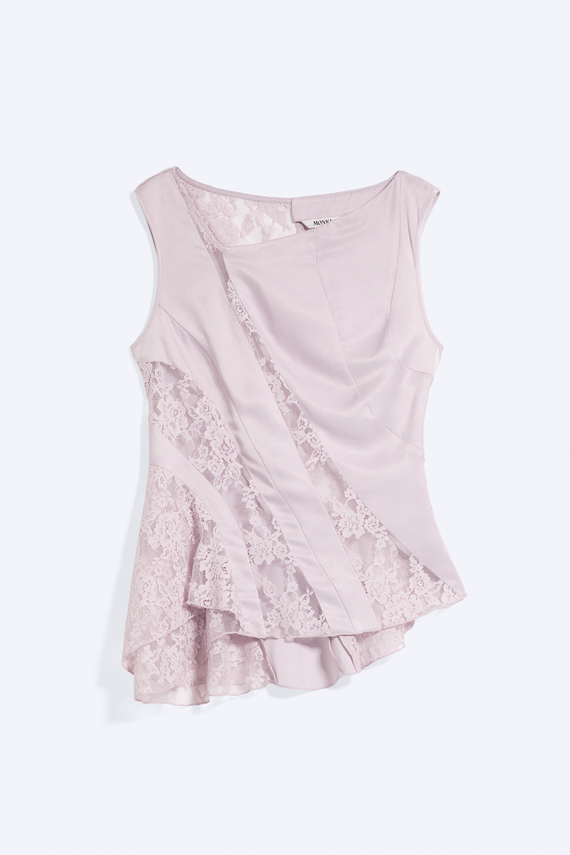 Un haut en satin sans manches, de couleur rose pâle, doté d'un col bateau, de panneaux asymétriques en diagonale et d'empiècements en dentelle florale transparente, est porté par le mannequin. Le haut est associé à un jean noir, mettant en valeur son ourlet évasé asymétrique.