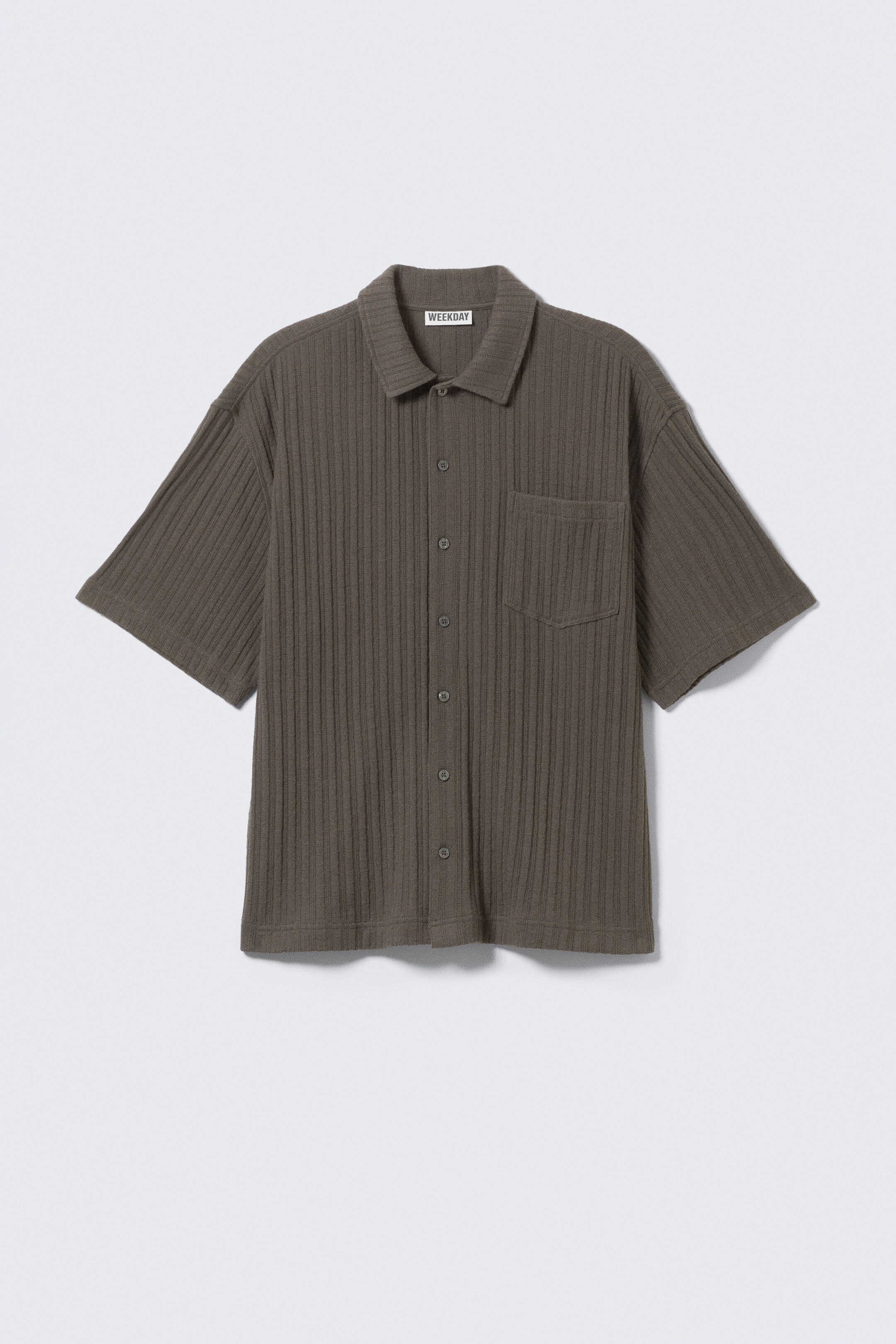 Ver imagen más grande: Se presenta una camisa de punto de manga corta de color verde oliva oscuro en una vista FRONTAL. Presenta una textura acanalada, un ajuste holgado, un cuello puntiagudo, una parte delantera con botones y un solo bolsillo en el pecho.