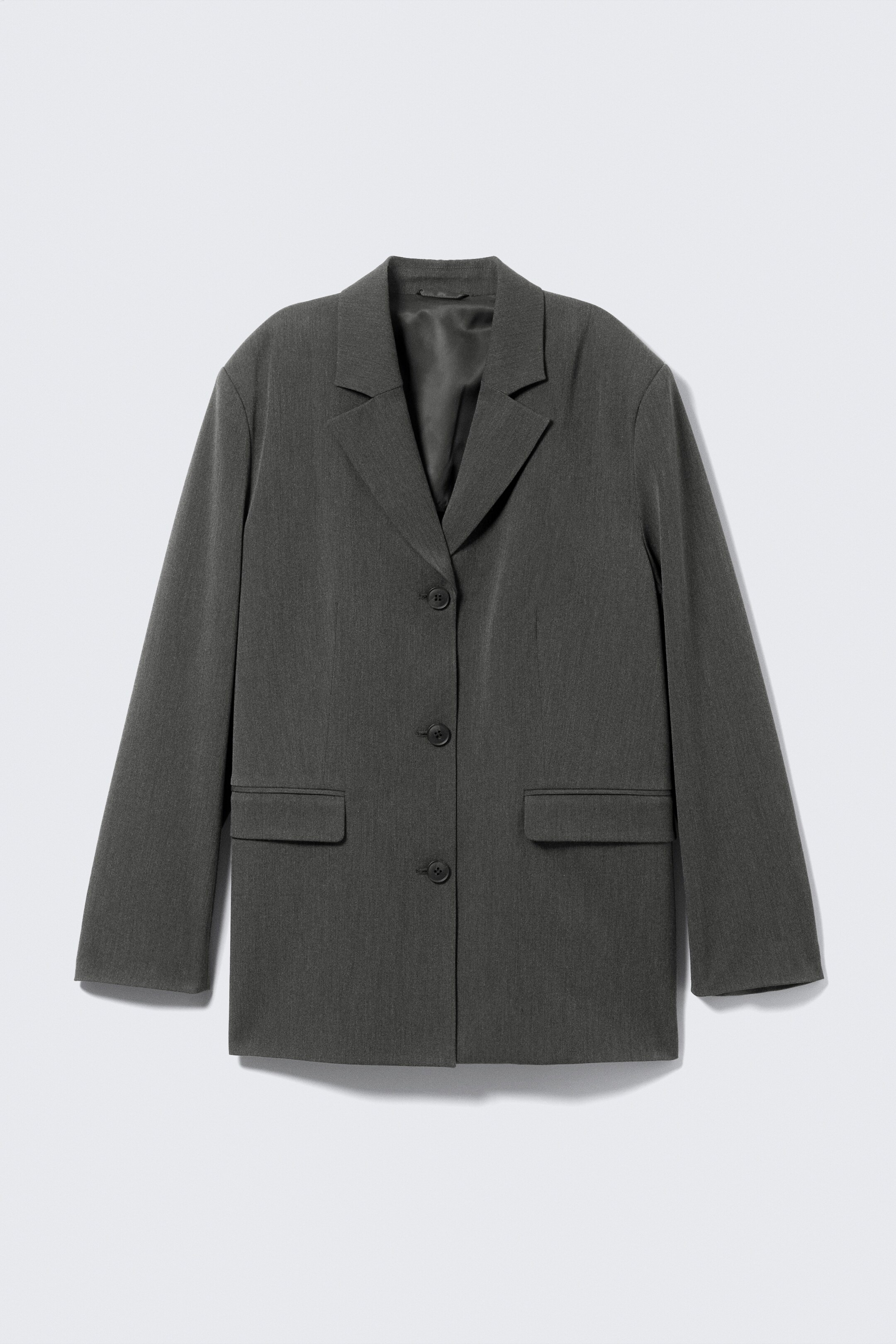 Größeres Bild anzeigen: Ein dunkelgrauer Blazer wird von vorne präsentiert, mit Kerbrevers, einem Drei-Knopf-Verschluss und zwei rechteckigen Pattentaschen.