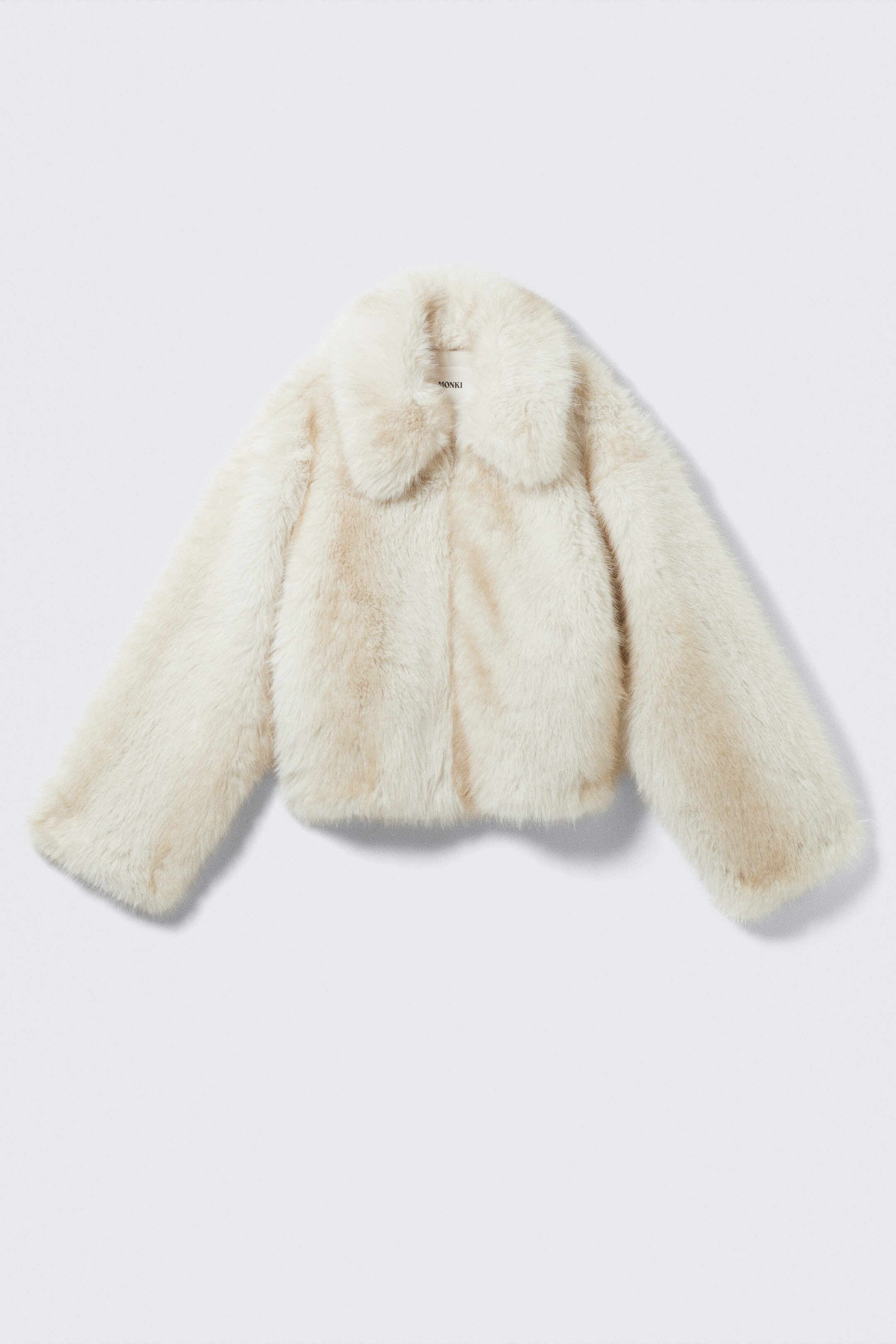 View larger image: A cropped, cream-toned faux fur jacket is shown from the front. It features a wide, rounded collar and long, slightly flared sleeves.
