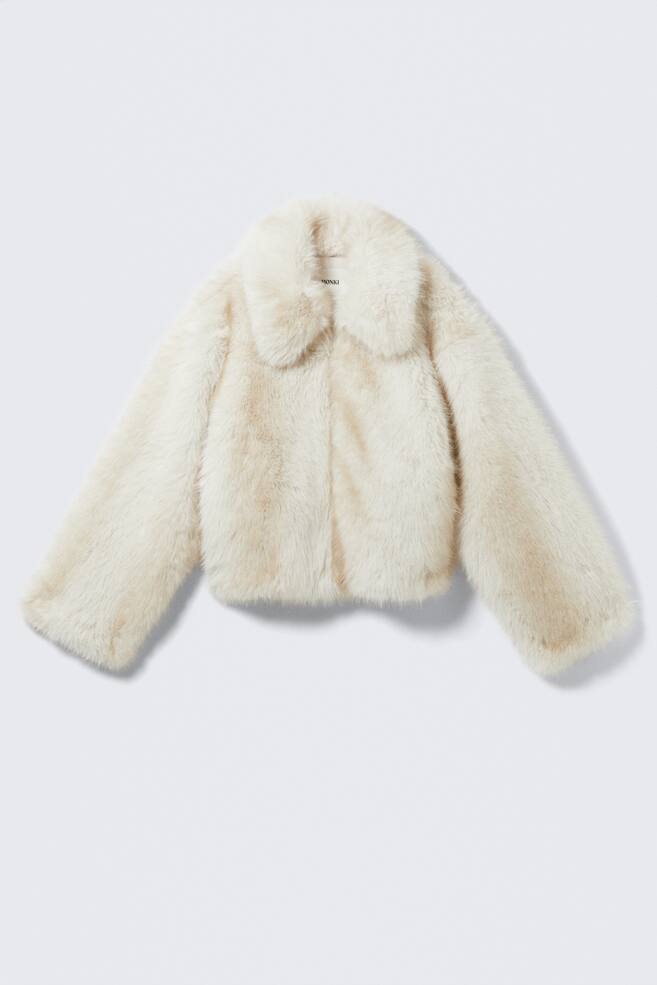 Eine abgeschnittene, cremefarbene Kunstpelzjacke wird von vorne gezeigt. Sie verfügt über einen breiten, abgerundeten Kragen und lange, leicht ausgestellte Ärmel. - 1