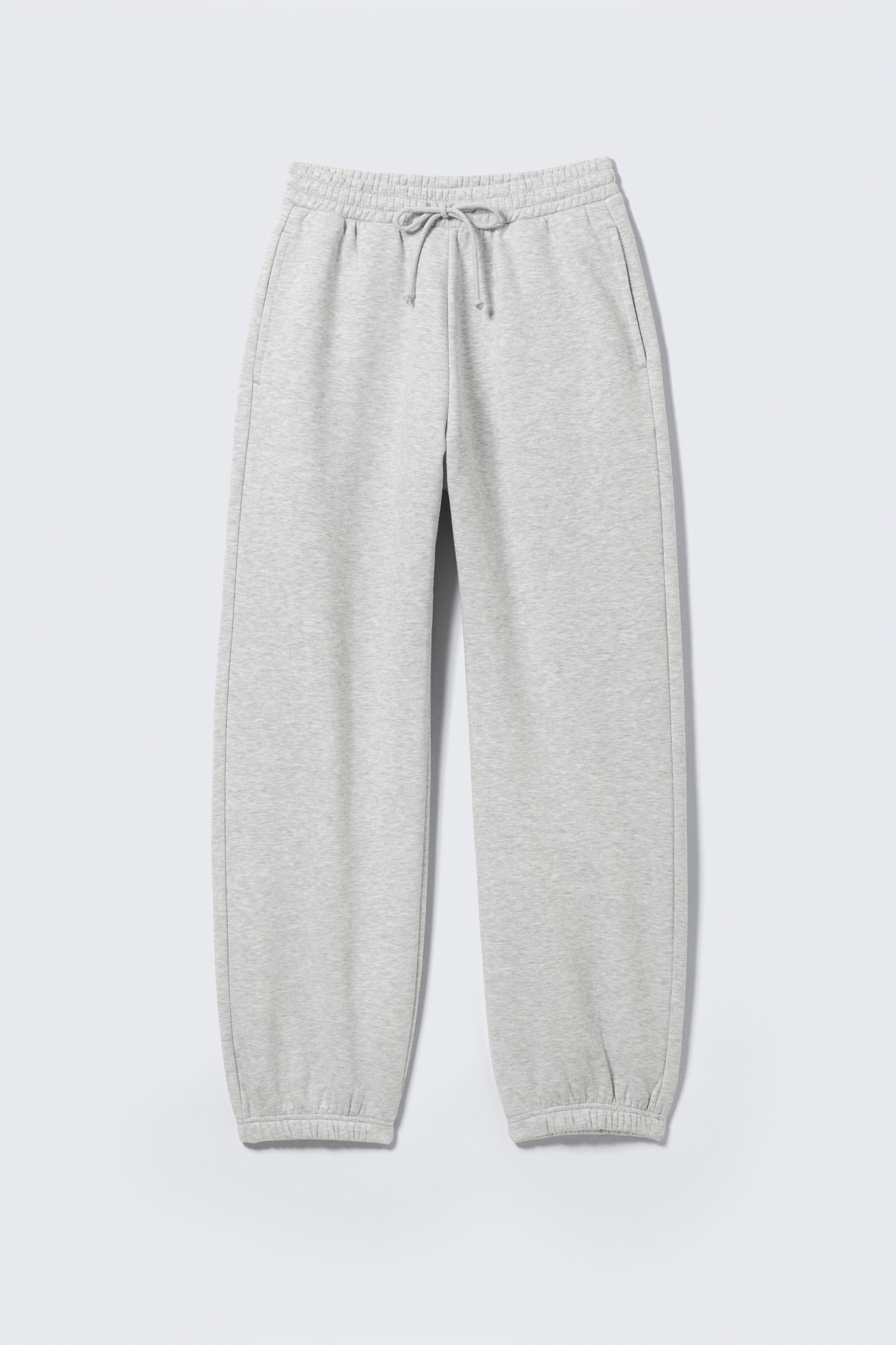 Se større billede: Et par lysegrå sweatpants af bomuldsfleece, præsenteret FRONT i en regular fit, har en elastisk linning med synlige snoretræk. Søm på hver hofte ses sidelommer, og benene afsluttes med elastiske manchetter.