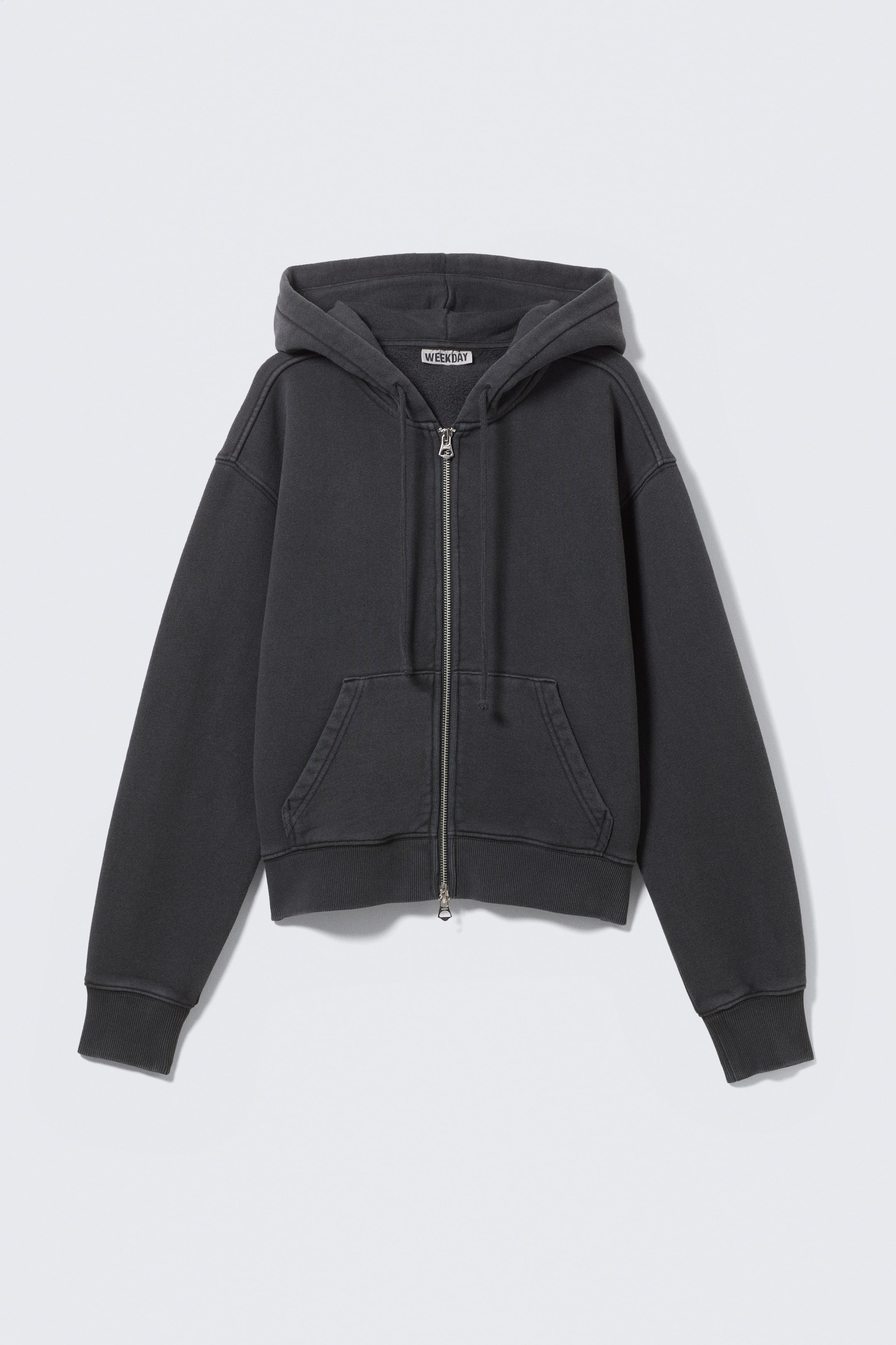 Ver imagen más grande: Una sudadera con capucha de color gris oscuro con cierre de cremallera se presenta de FRENTE, con una capucha, una cremallera de metal de tono plateado de largo completo, un bolsillo canguro dividido y puños y dobladillo acanalados, con la tela que parece ligeramente desgastada.