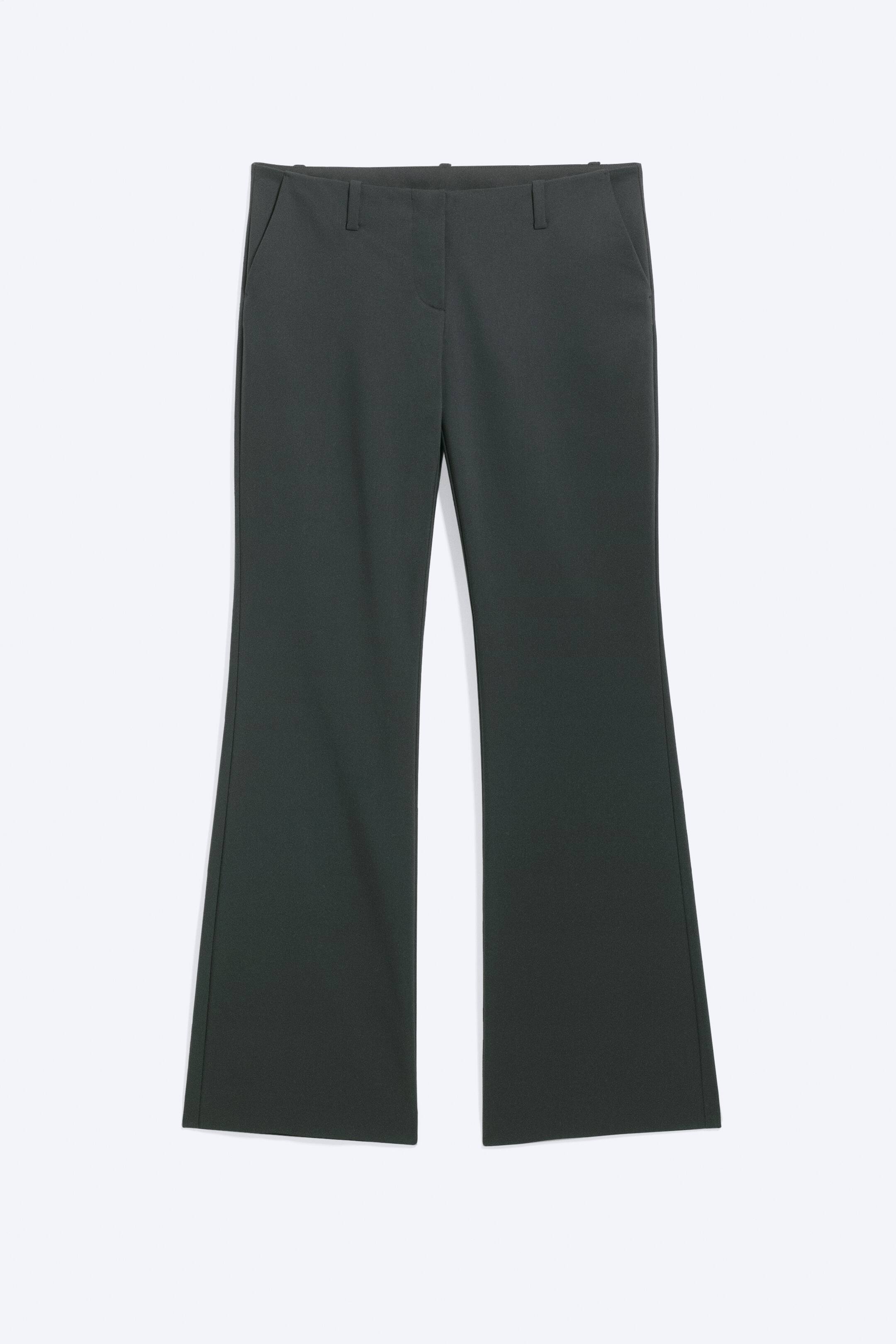 Grotere afbeelding bekijken: Deze donkergrijze bootcut pantalons met lage taille zijn van voren afgebeeld en tonen een gestructureerde tailleband met riemlussen en steekzakken aan de zijkant. De pijpen sluiten nauw aan op de bovenbenen en lopen vanaf de knieën licht uit voor een klassieke bootcut-silhouet.