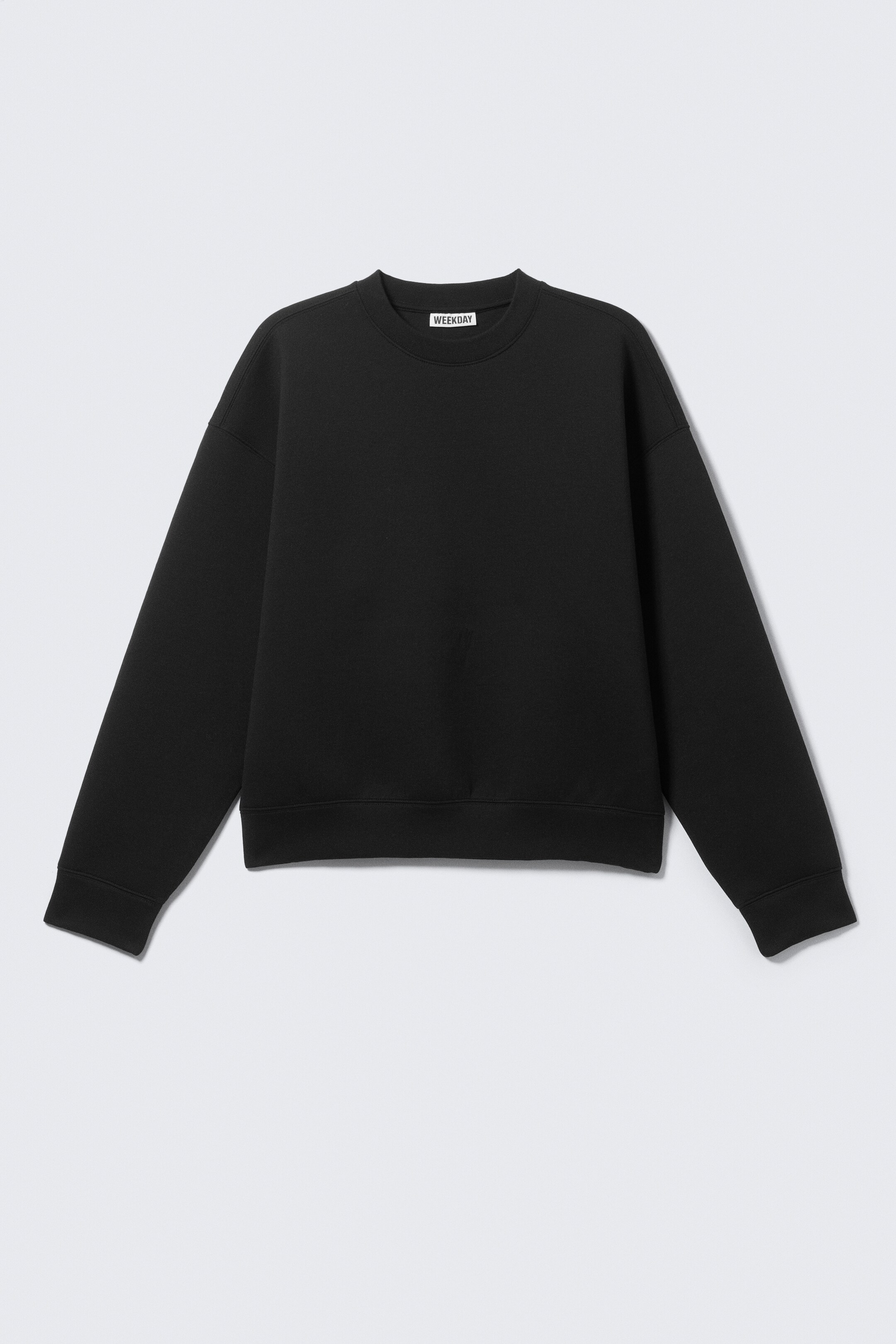 Se større billede: En sort sweatshirt med rund hals er præsenteret FORFRA, og har en klassisk rund hals, lange ærmer med ribbede manchetter og en ribbet kant.