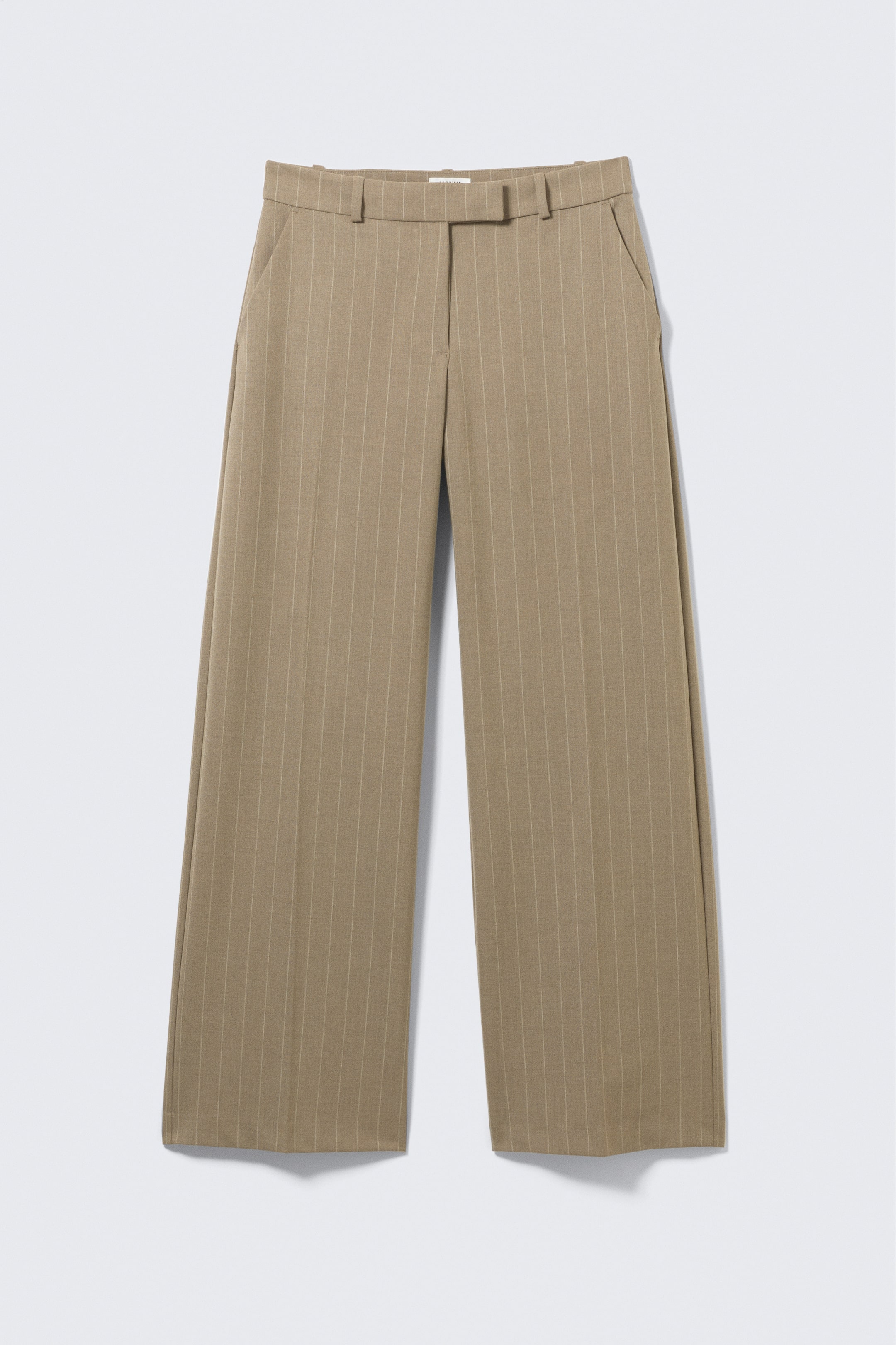 View larger image: A pair of beige pinstriped low-rise suiting trousers is showcasing a straight leg and structured fabric, viewed from the front. They feature slanted side pockets, pressed creases running down the front, and a clean waistband with a hook-and-bar fastening.