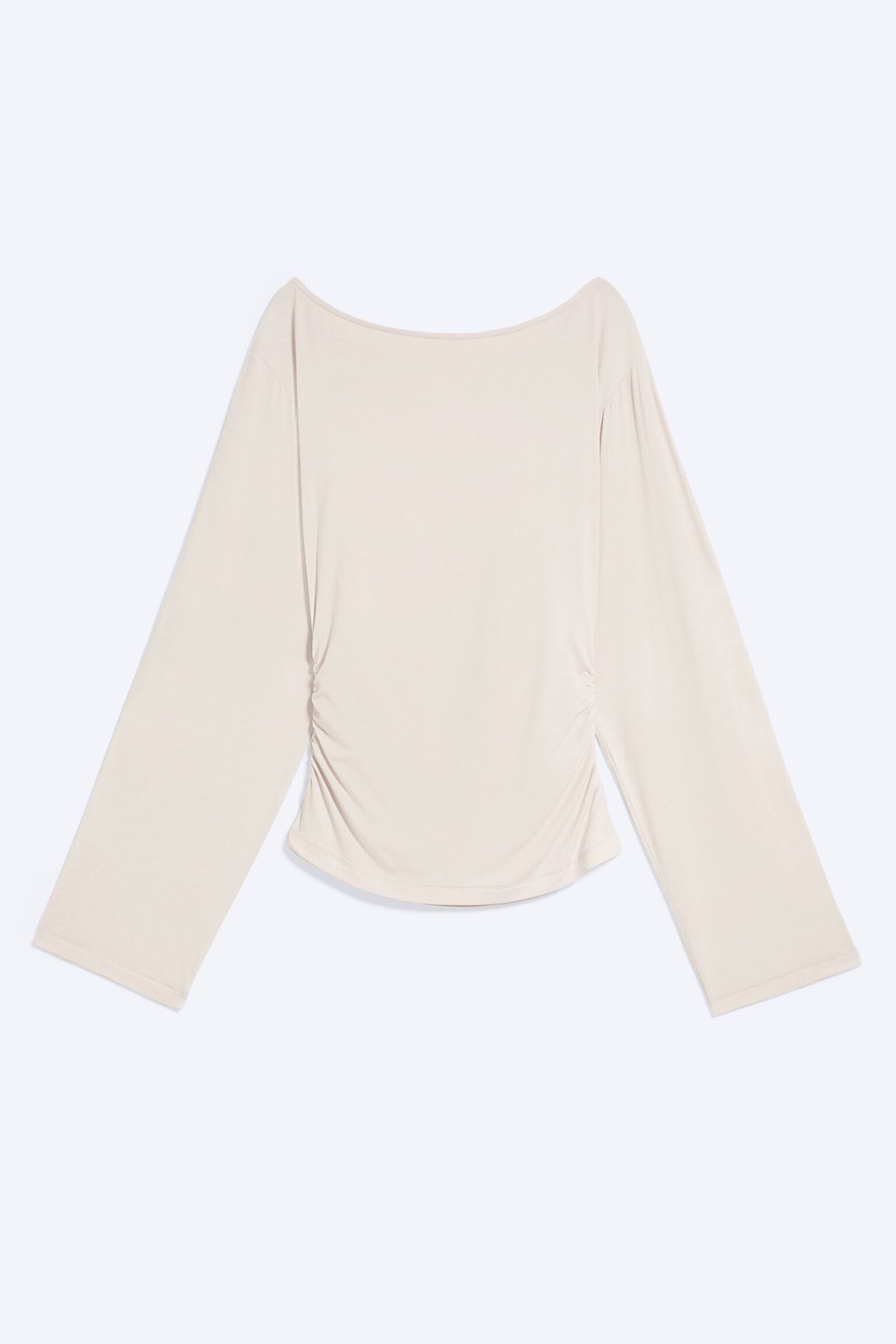 Un haut cintrÃ© Ã  manches longues, couleur beige clair, est prÃ©sentÃ© de face, avec un large col bateau et de longues manches amples. Le modÃ¨le prÃ©sente des fronces froncÃ©es de part et dâautre de la taille, crÃ©ant un effet drapÃ© qui se resserre vers un ourlet arrondi.