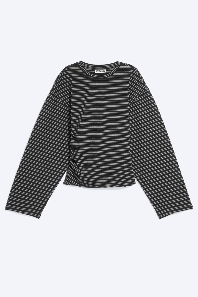 Ein Langarm-T-Shirt in einem dunkelgrau-weiÃen horizontalen Streifenmuster ist von vorne zu sehen und verfÃ¼gt Ã¼ber einen Rundhalsausschnitt, Ã¼berschnittene Schultern und weite Ãrmel. Das Shirt ist mit einer Raffdetail-Verarbeitung entlang einer Seitennaht gestaltet, wodurch Ã¼ber dem Oberteil ein dezenter Drapierungseffekt entsteht. - 1