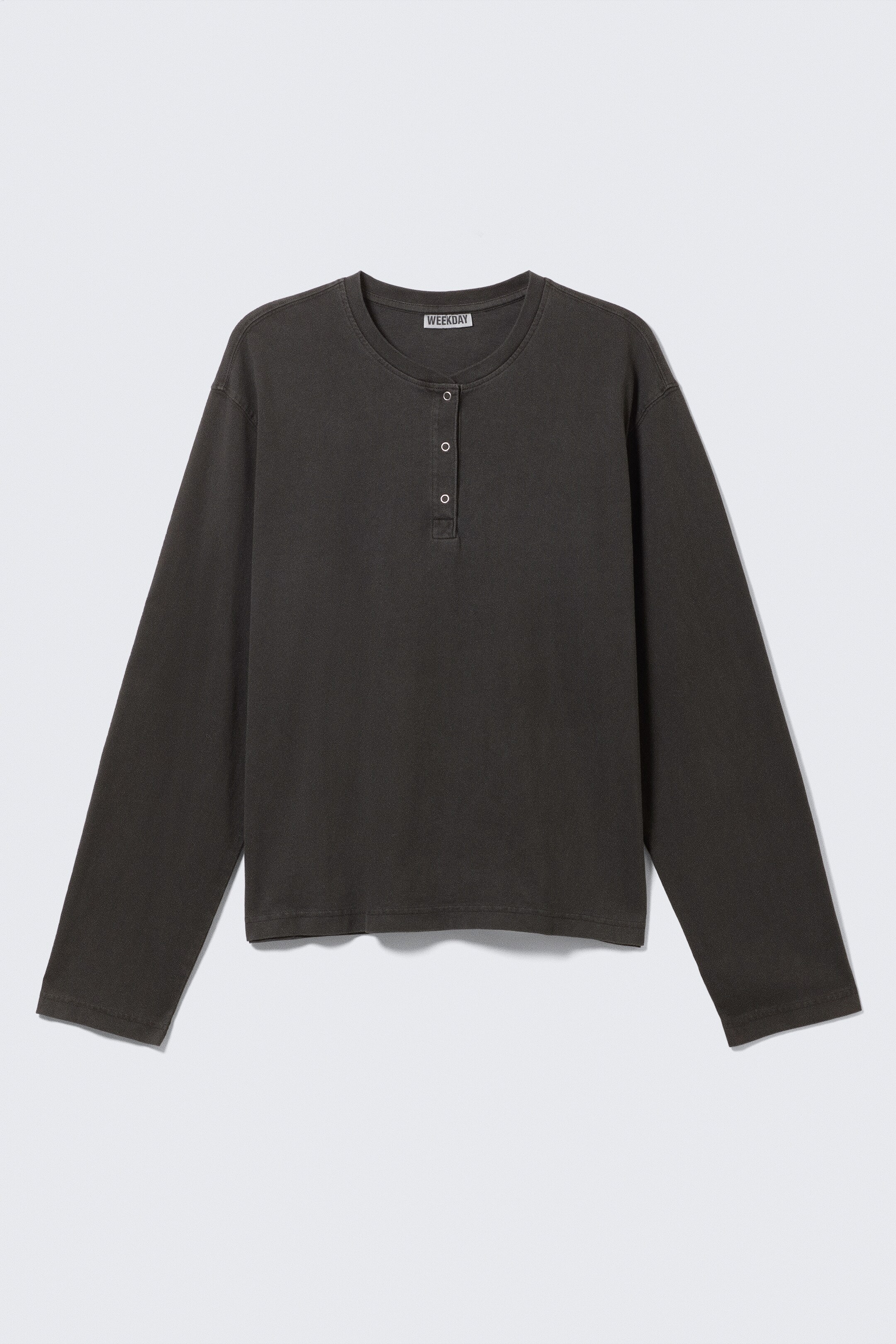 Grotere afbeelding bekijken: Een donkergrijze Henley met lange mouwen wordt frontaal gepresenteerd, met een ronde halslijn en een knoopsluiting met drie knopen. Het heeft lange mouwen en een rechte zoom, terwijl een "WEEKDAY" label zichtbaar is aan de achterkant van de nek.