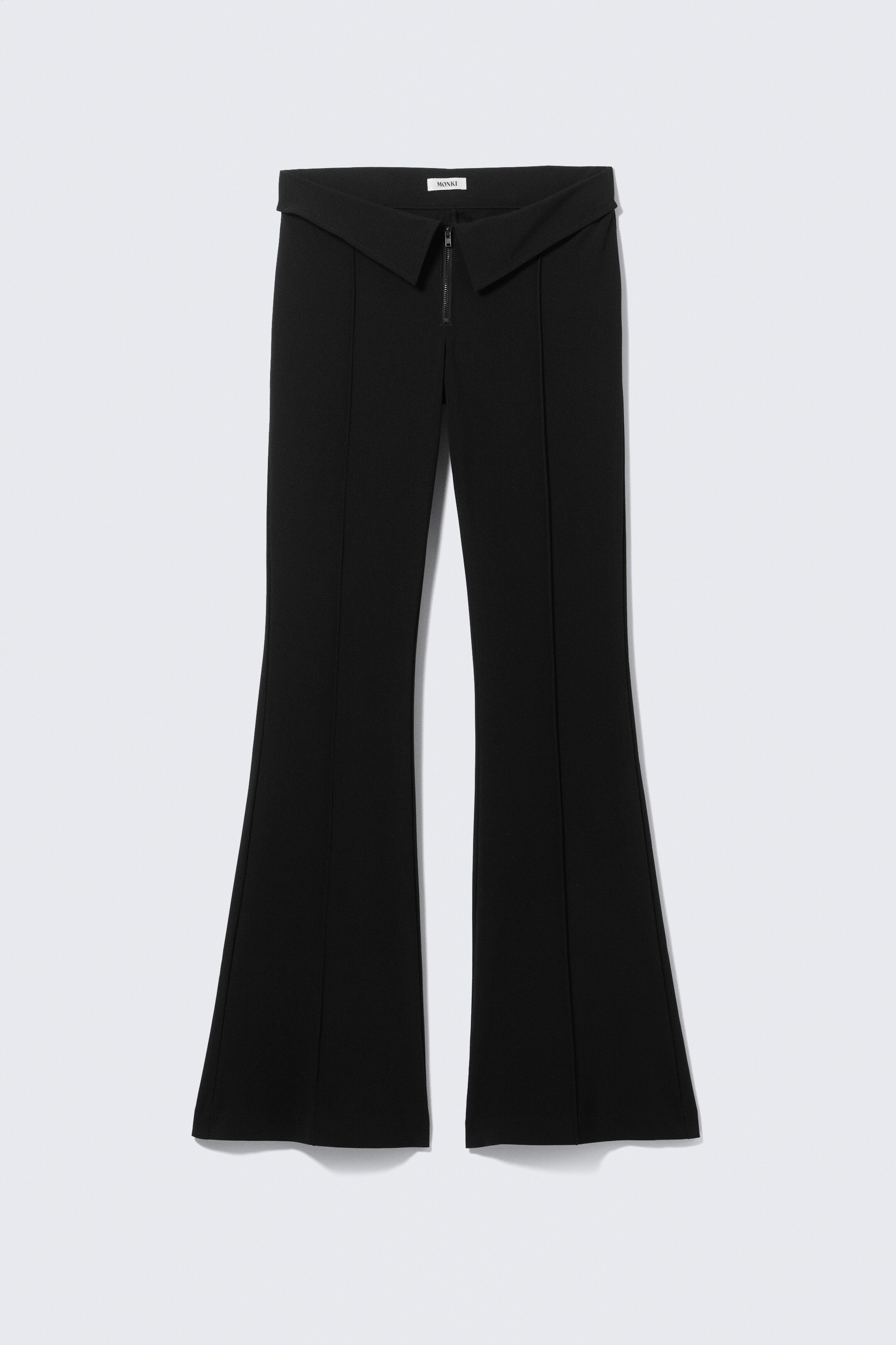 Agrandir l'image: Le pantalon noir évasé présente une large ceinture avant en forme de V avec une fermeture éclair centrale. Des coutures verticales descendent le long de l'avant de chaque jambe, s'évasant du genou à l'ourlet.