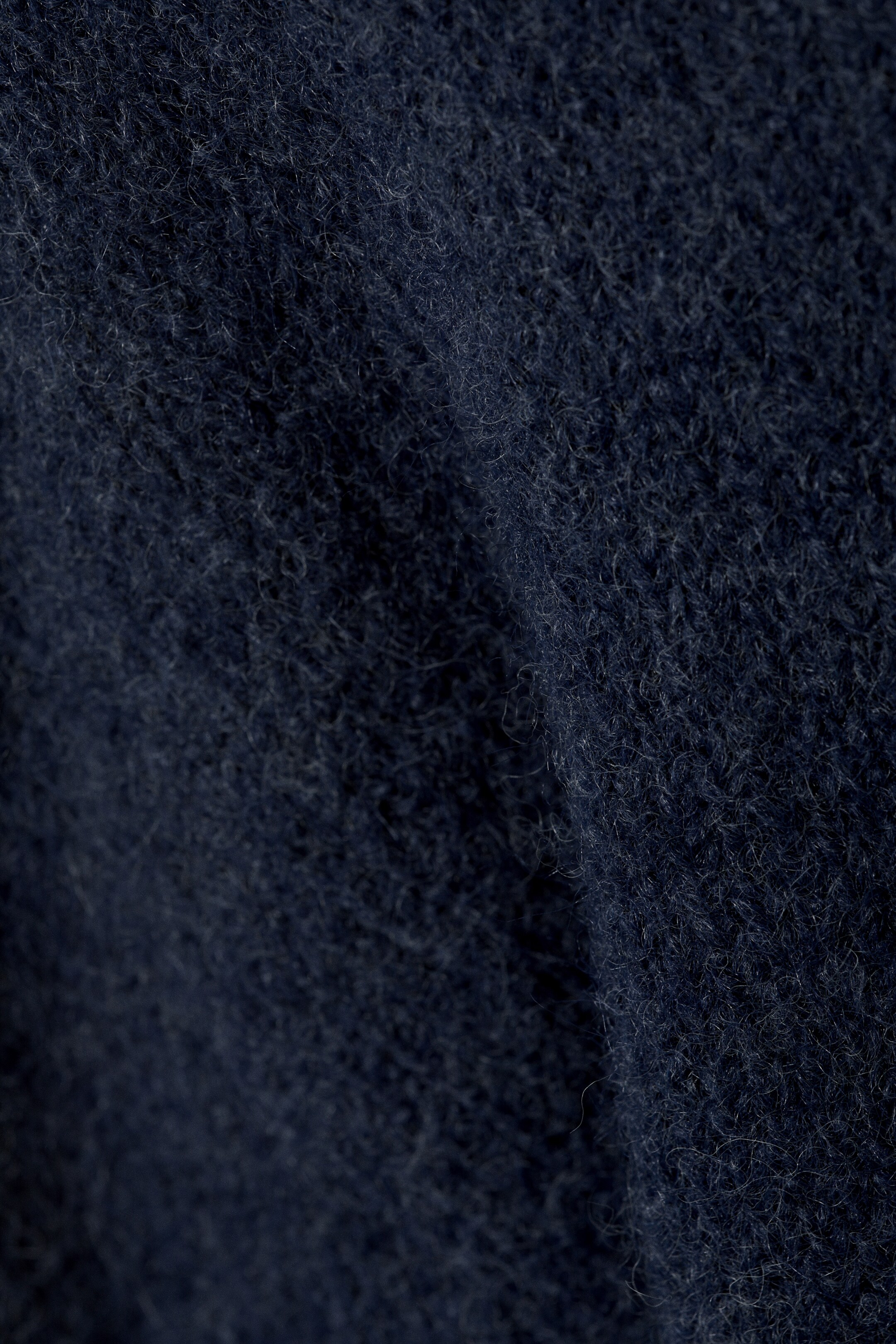 Ver imagen más grande: Una tela azul oscuro se muestra en un primer plano, enfatizando su textura suave y peluda. La superficie muestra un denso vello de fibras cortas y levantadas, creando una apariencia lujosa.