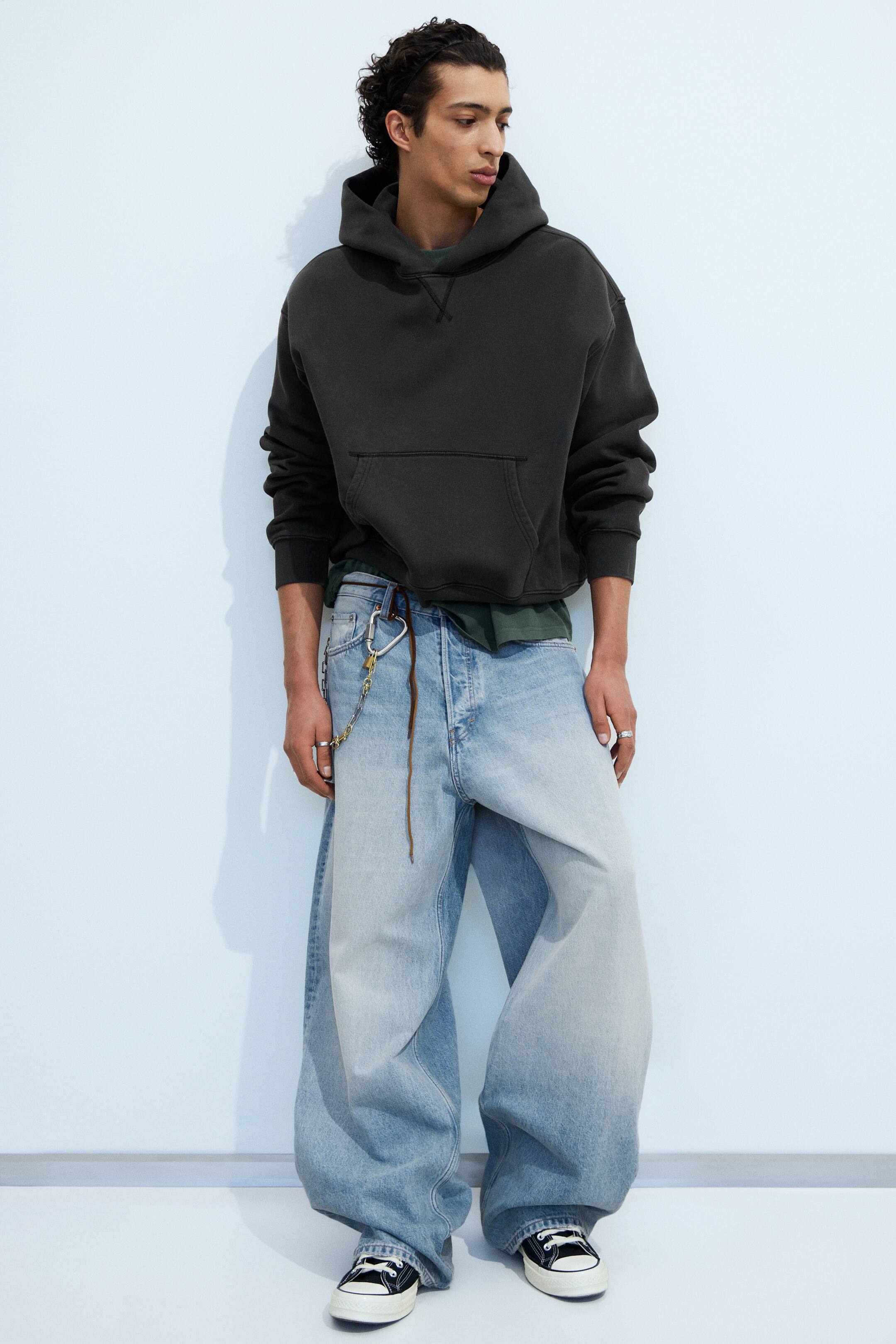 Agrandir l'image: Jean en denim bleu clair délavé présentant une coupe ample et évasée avec un effet ombré, s'estompant du plus foncé à la taille haute au plus clair vers les ourlets. Une cordelette marron et un accessoire chaîne en métal sont attachés aux passants de ceinture à l'avant.