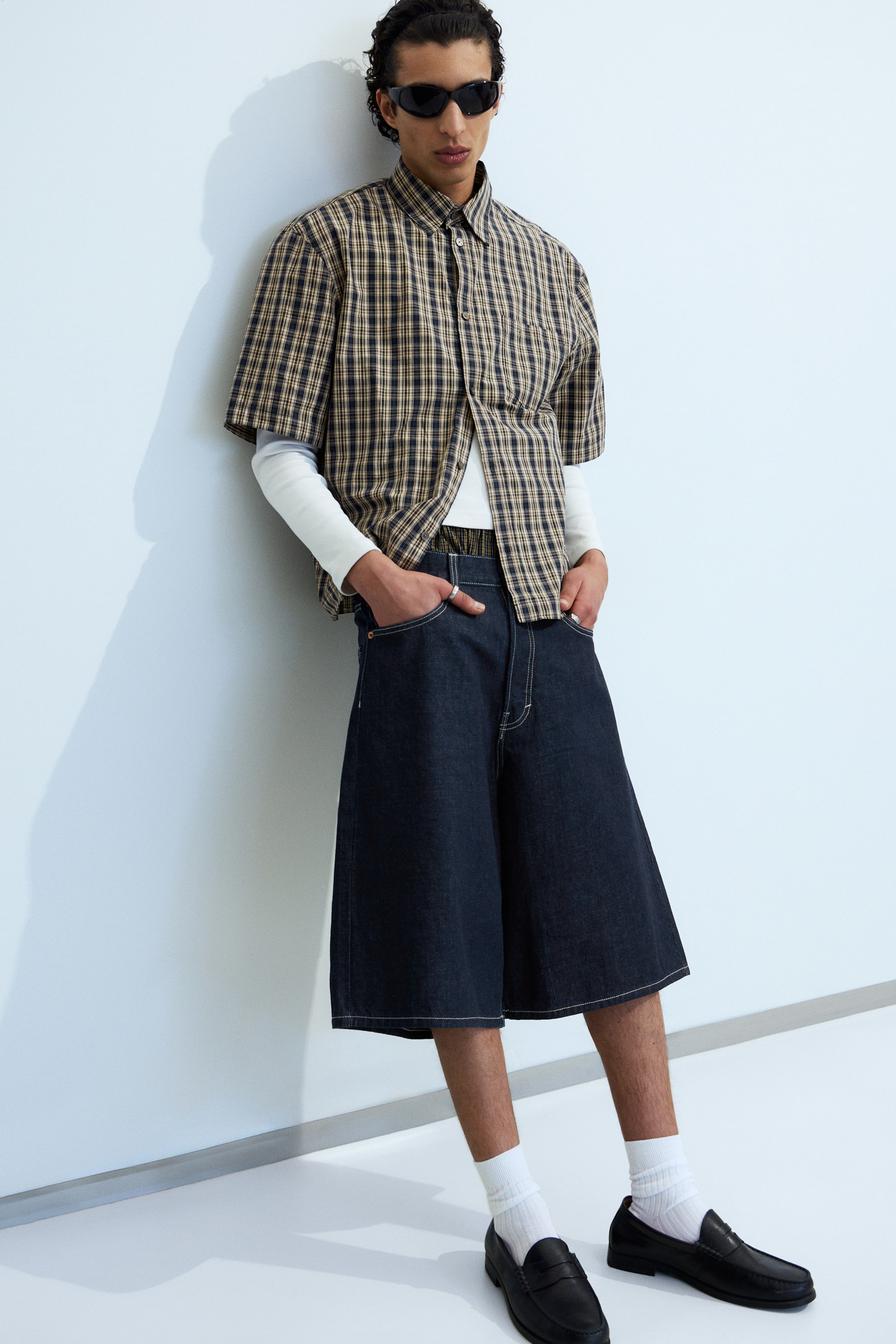 View larger image: Dark wash denim culottes are showcased from a slight front-left angle, featuring wide legs, contrasting white stitching along the seams and front pockets, and extending to just above the knee.
