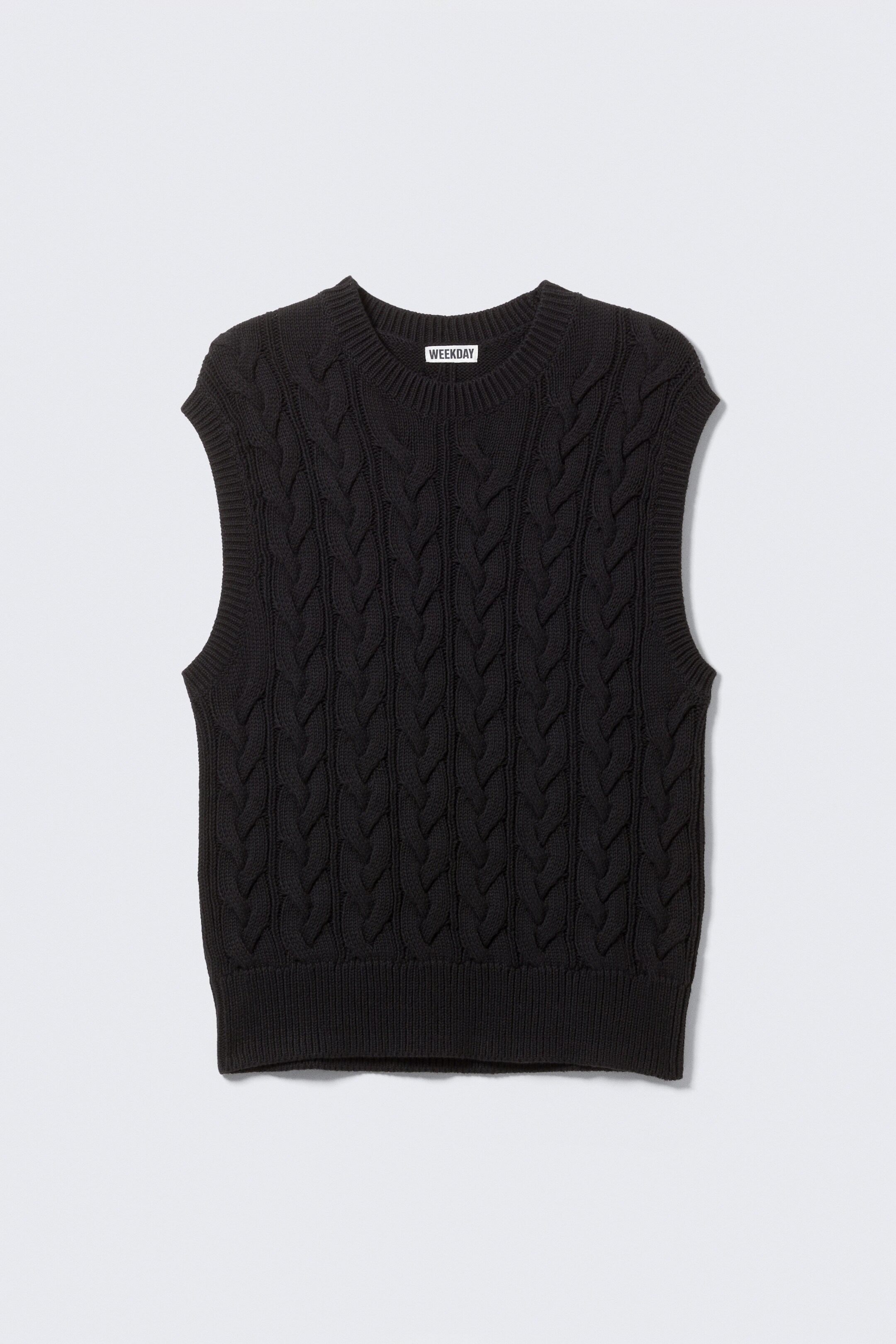 Visualizza immagine più grande: Un gilet nero a maglia con trecce mostra la sua vista frontale. Presenta uno scollo a girocollo, un'etichetta del marchio "WEEKDAY" visibile all'interno della scollatura e bordi a coste lungo lo scollo, le asole e l'orlo inferiore.