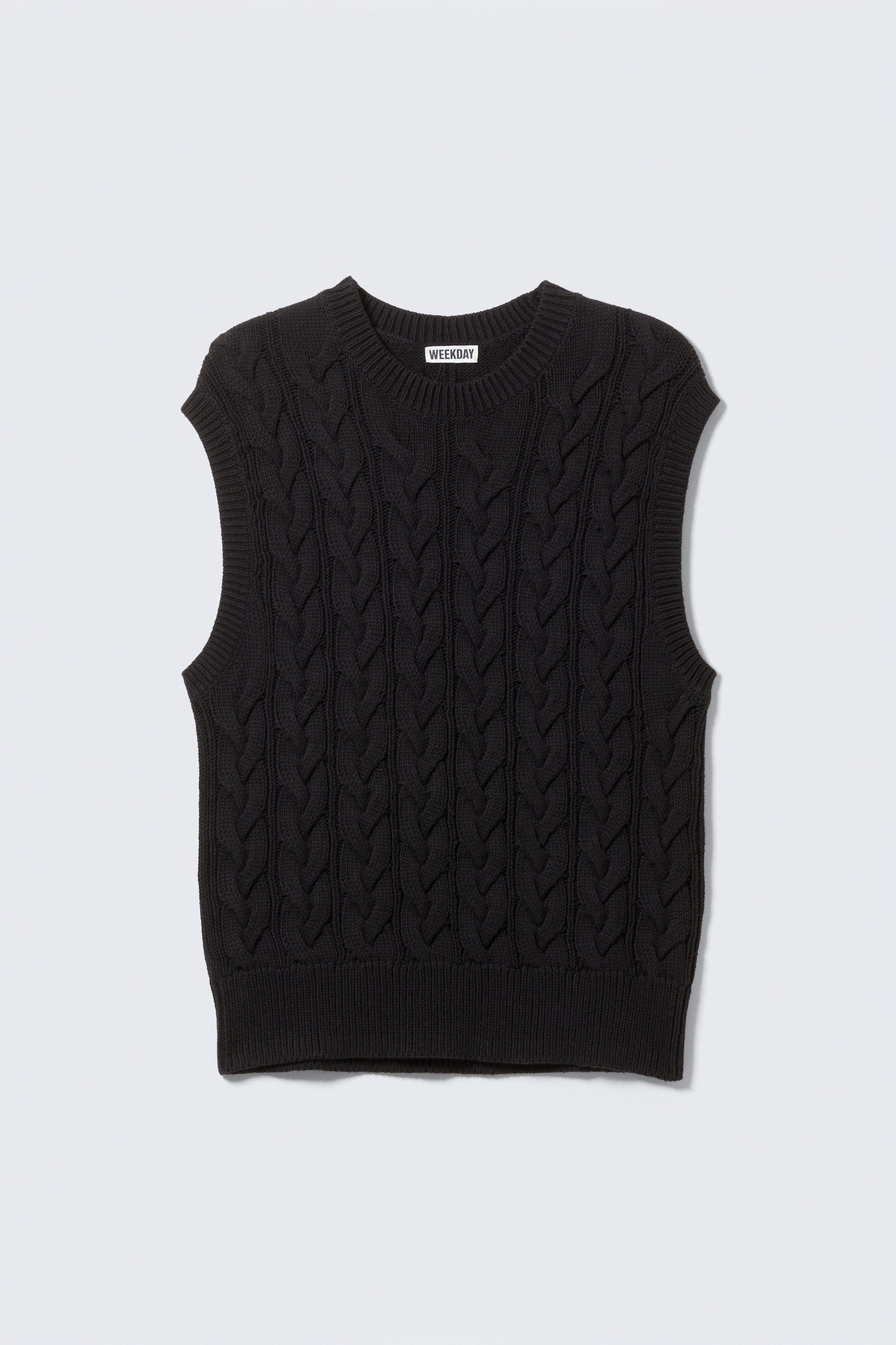 Se større billede: En sort kabelstrikket sweatervest vises fra forsiden. Den har en rund hals, et "WEEKDAY" mærkemærke synligt inde i halsudskæringen, og ribbede kanter langs halsudskæringen, ærmegabene og bundkanten.