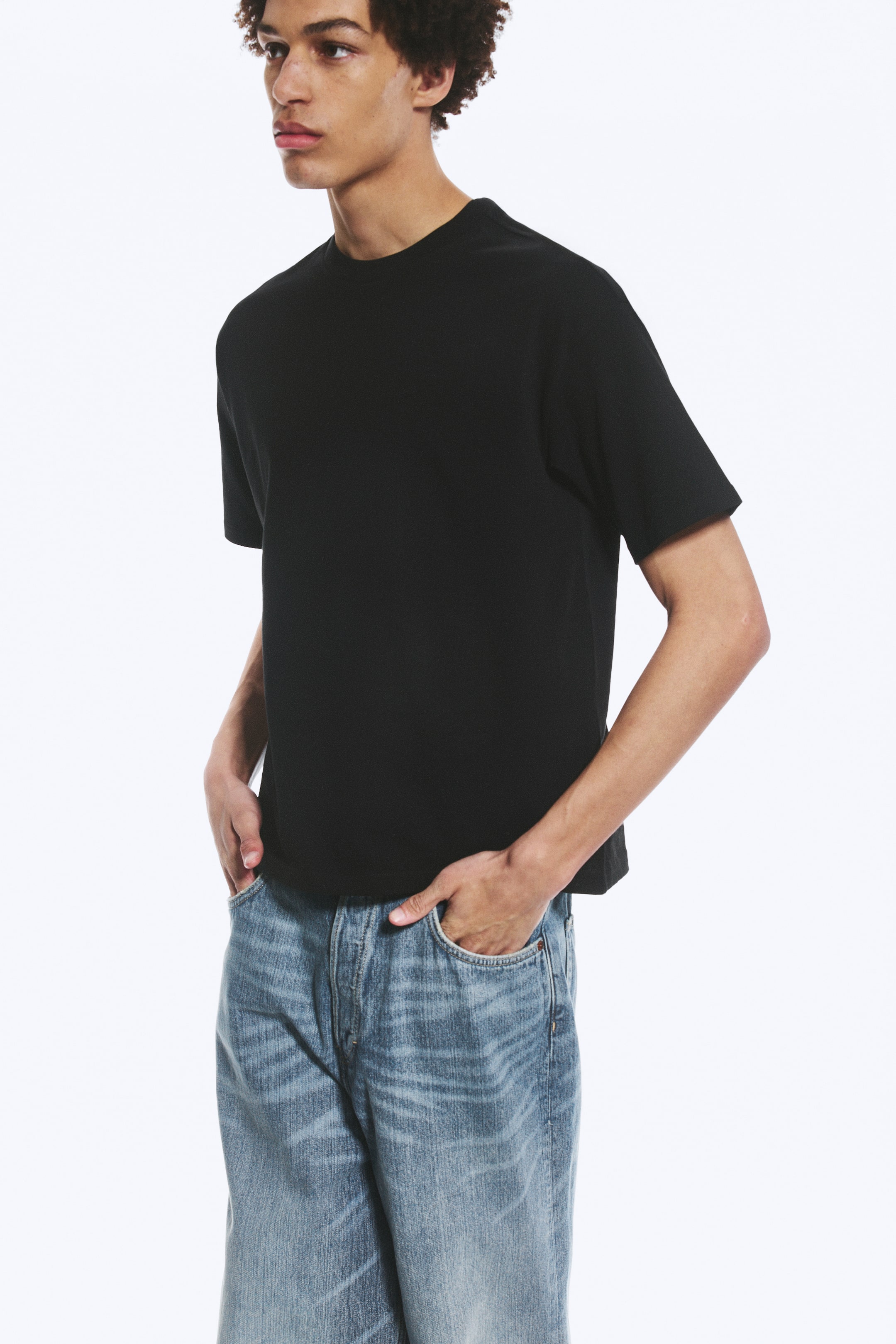 Se større billede: En sort t-shirt med rund hals, korte ærmer og en afslappet pasform med lige kant, præsenteret fra en let frontside vinkel.