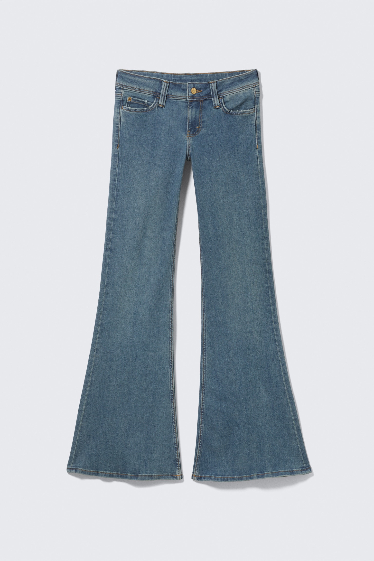 Een paar mediumblauwe denim jeans toont zijn VOORKANT, met een lage taille, een skinny fit door de dij en een wijde flare vanaf de knie tot een lange lengte. De jeans heeft een zichtbare ritssluiting, een enkele knoopsluiting, riemlussen en twee voorzakken met een muntzakje.