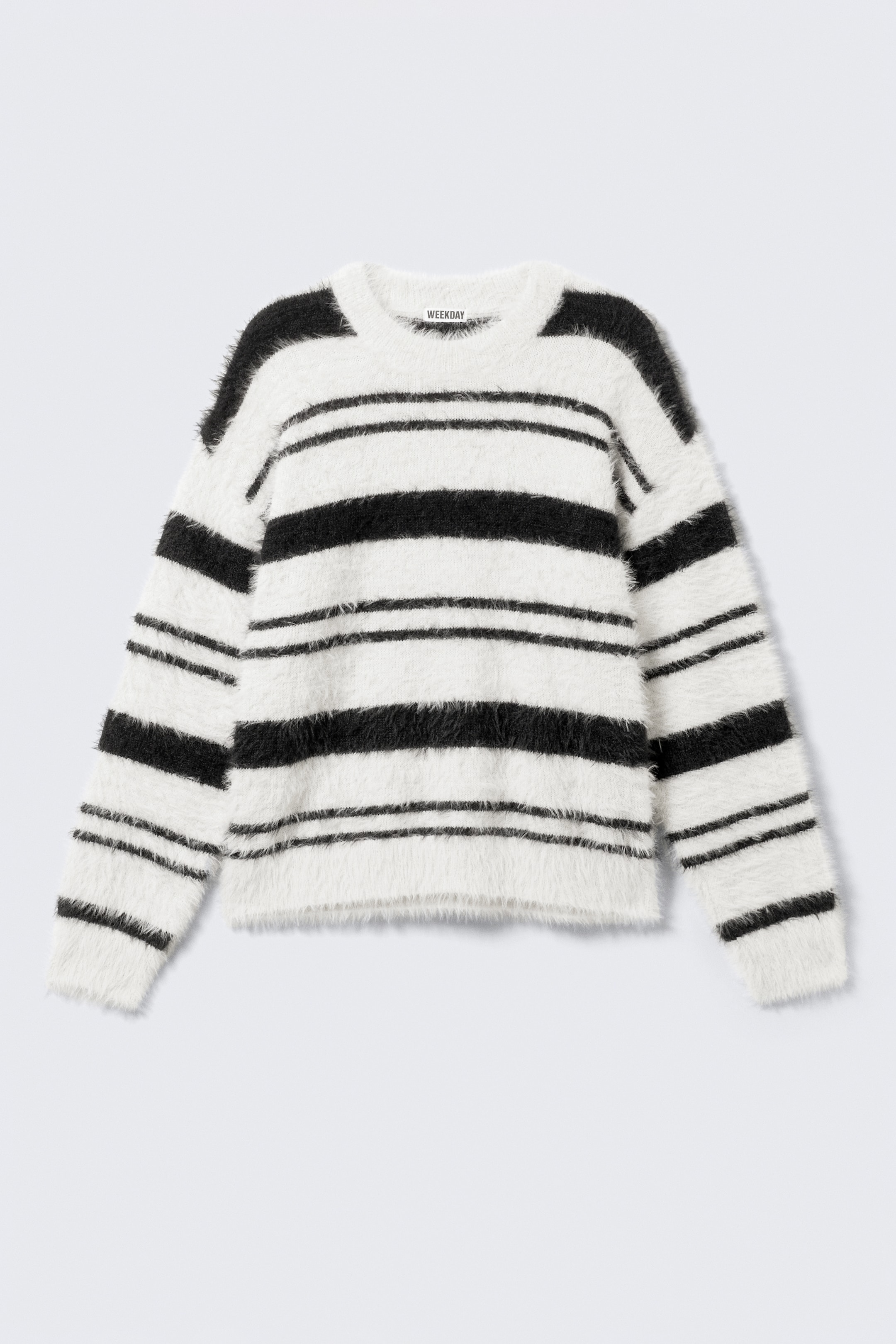 Größeres Bild anzeigen: Ein gestrickter Pullover, nach VORN gerichtet, zeigt eine weiche, gebürstete Textur mit schwarzen und weißen horizontalen Streifen. Er verfügt über eine lockere Passform, überschnittene Schultern, einen klassischen Rundhalsausschnitt sowie gerippte Bündchen und einen gerippten Saum.