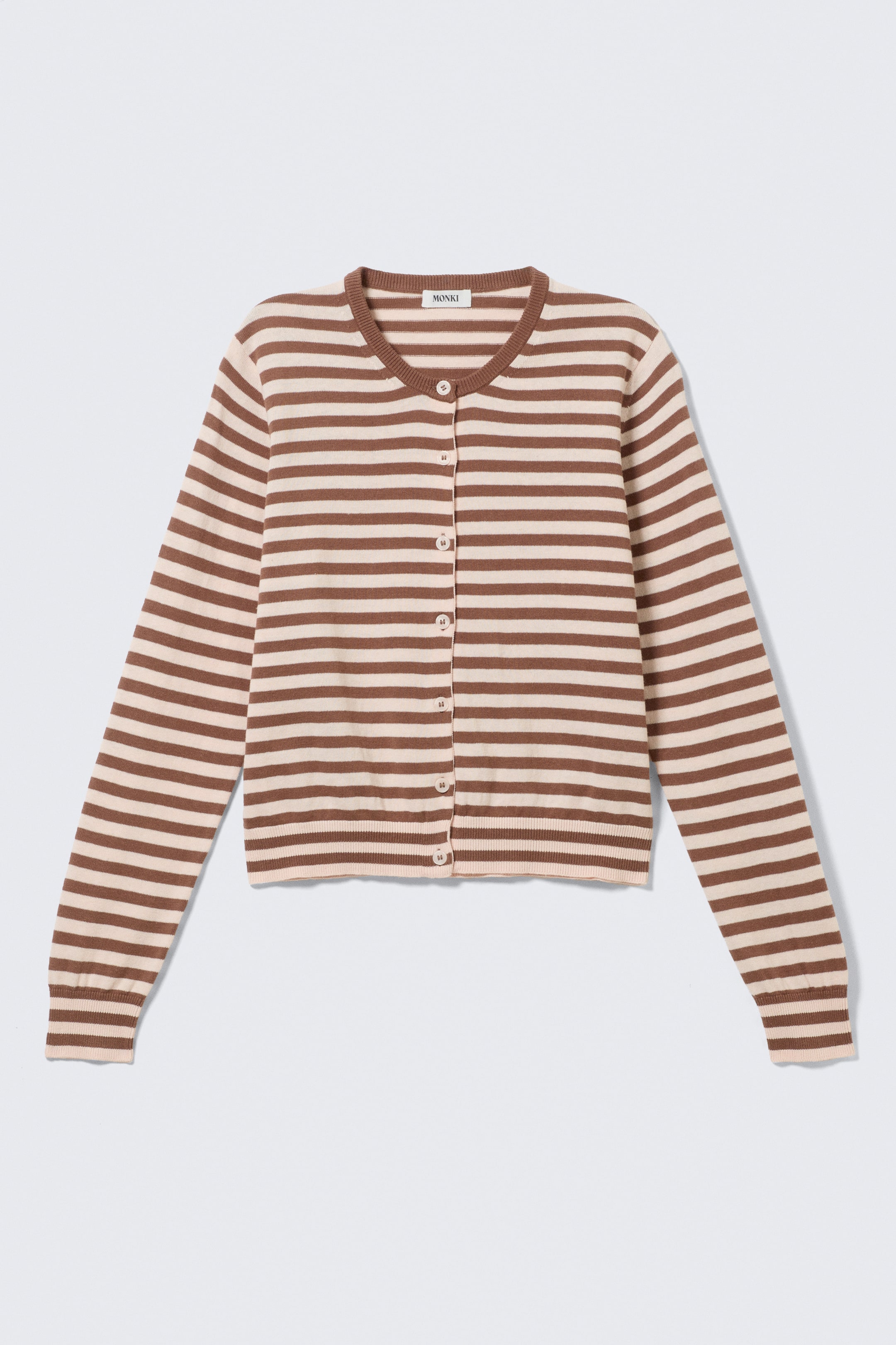 Ver imagen más grande: Un cárdigan de rayas horizontales en tonos marrón y beige se presenta en vista frontal, mostrando un cuello redondo, mangas largas con puños acanalados y un dobladillo acanalado. Una etiqueta de la marca "MONKI" es visible en la parte trasera del cuello, y una fila de pequeños botones de color claro recorre el centro del frente.