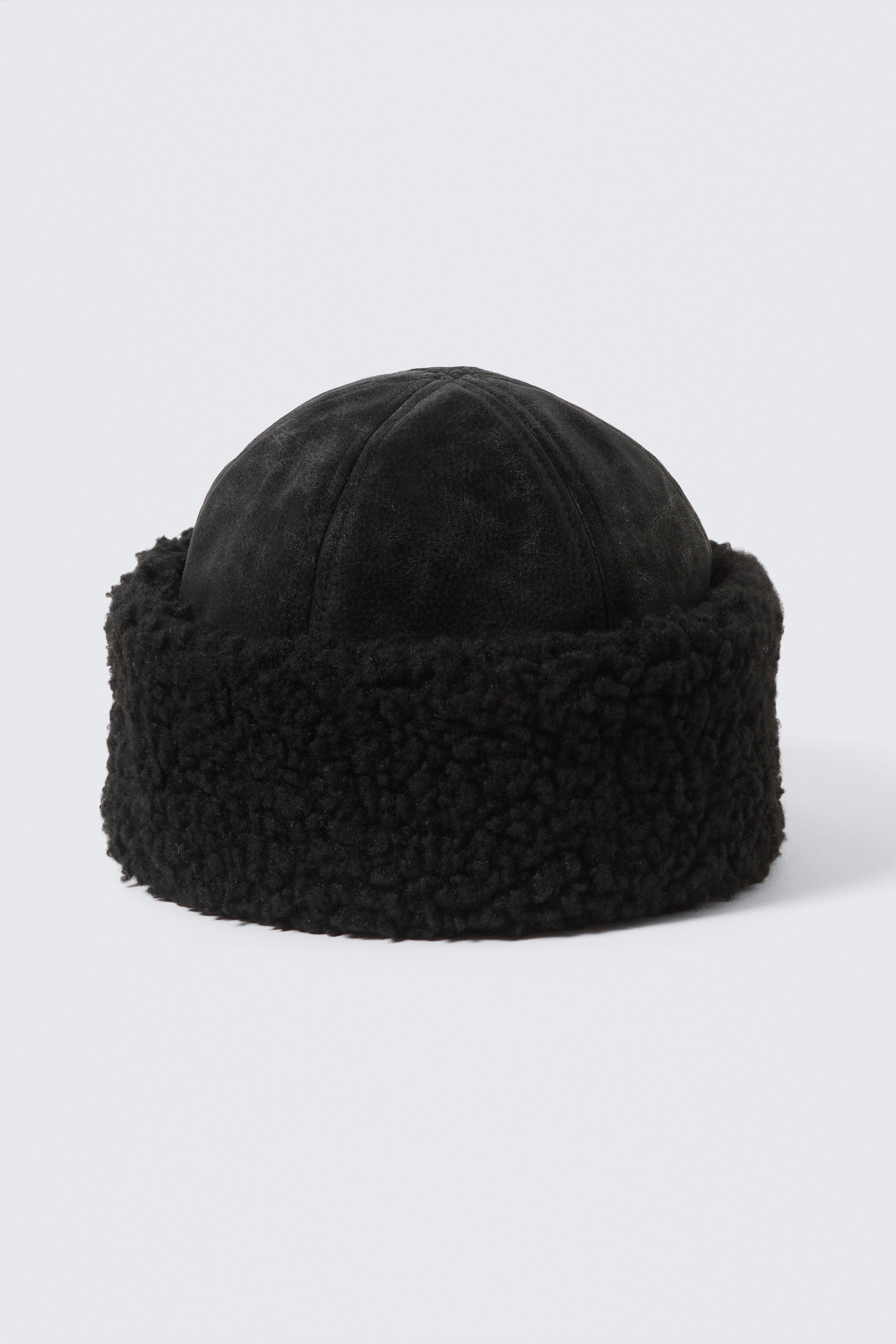 Ver imagen más grande: Un sombrero de piel sintética negra presenta su PARTE DELANTERA, con una corona de pelo corto y panelada con costuras visibles y un ala peluda y doblada que mide aproximadamente 7 cm.