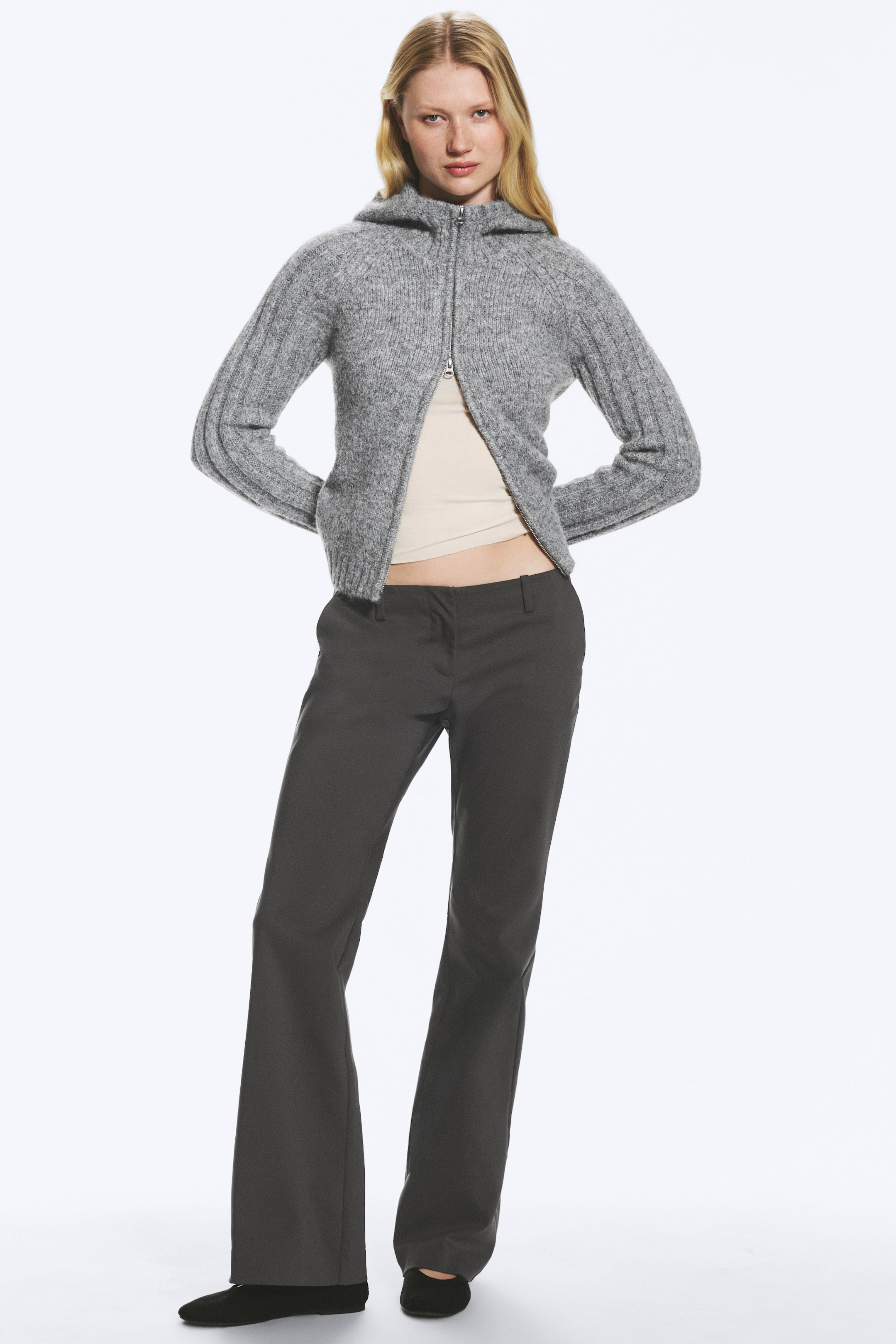 Visualizza immagine più grande: I pantaloni da completo a vita bassa e gamba bootcut in grigio scuro sono indossati dalla modella, con davanti liscio e un leggero svaso dal ginocchio all’orlo.