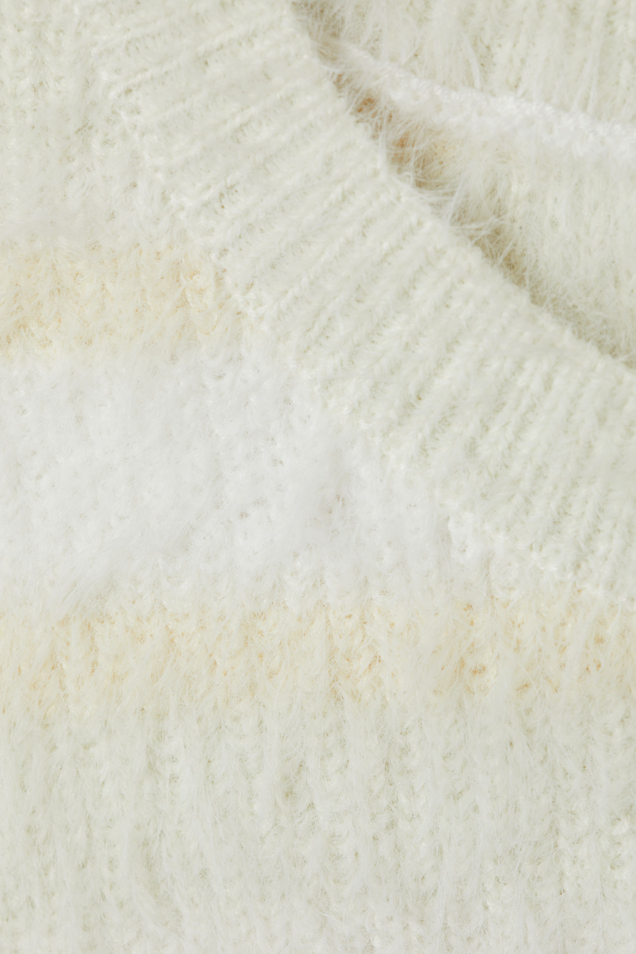 Se større billede: En cremefarvet, fuzzy sweater har subtile horisontale striber i en lysere beige. En ribbet V-halskrave er synlig øverst.