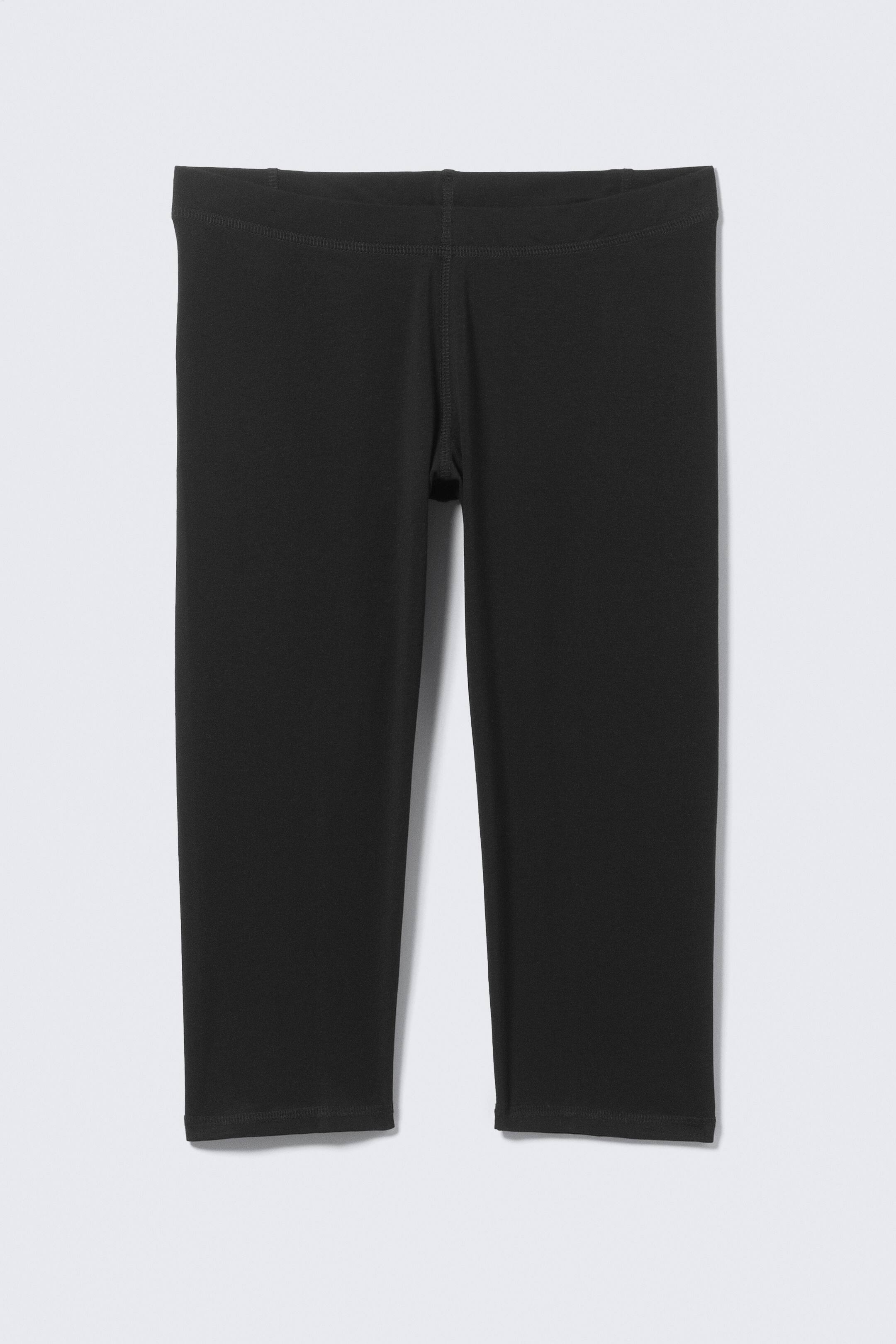 Visualizza l'immagine ingrandita: "I leggings capri neri sono presentati FRONTE, caratterizzati da un design liscio e aderente con una fascia in vita ampia e piatta e una lunghezza che termina appena sotto il ginocchio."