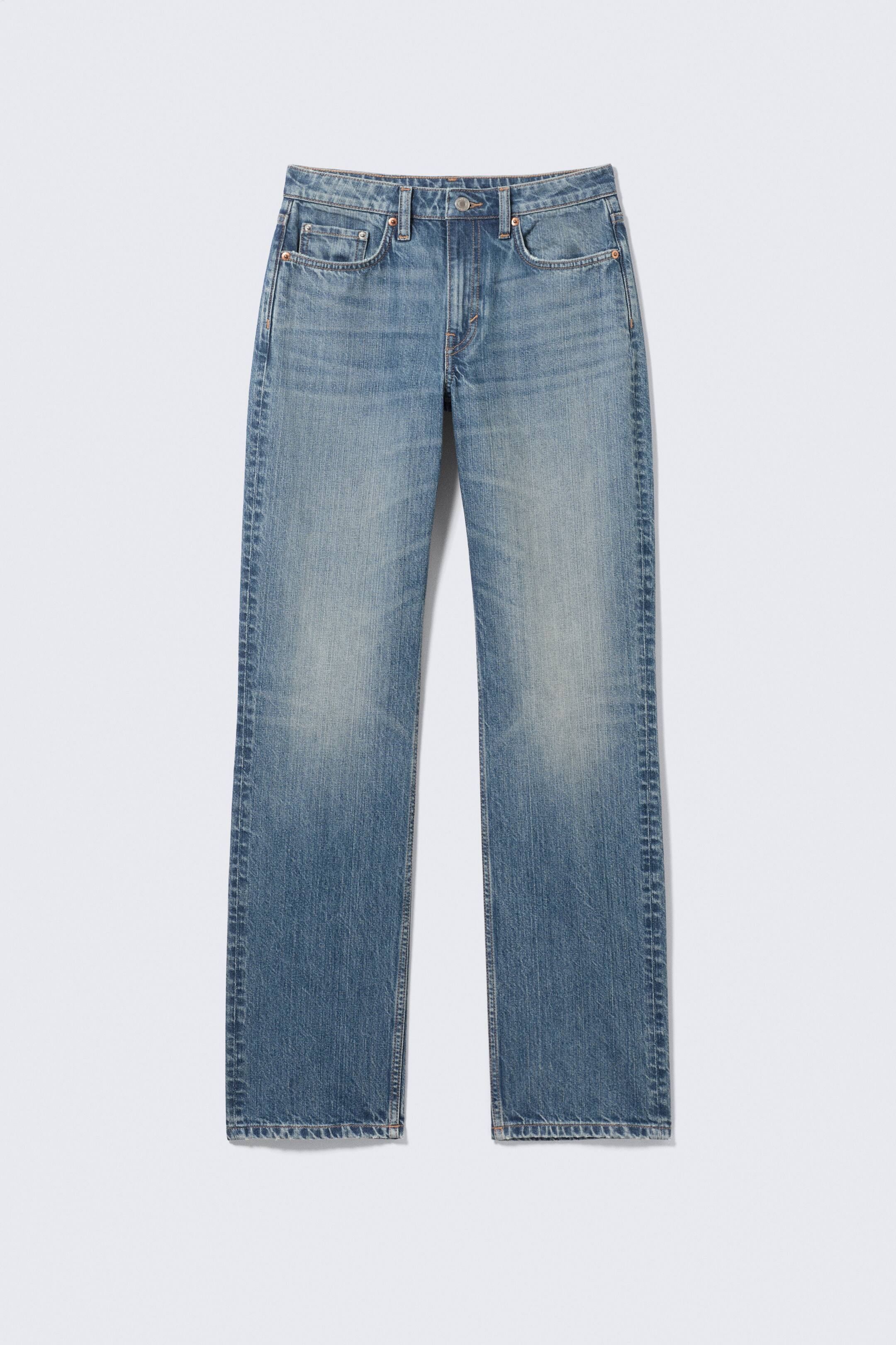 Grotere afbeelding bekijken: Een paar blauwe jeans ligt plat met de voorkant naar voren gericht, en toont een middelblauwe wassing met lichtere vervaging op de bovenbenen. De jeans heeft een rechte pijp, twee voorzakken, een muntzakje, riemlussen, een metalen knoop en een ritssluiting.