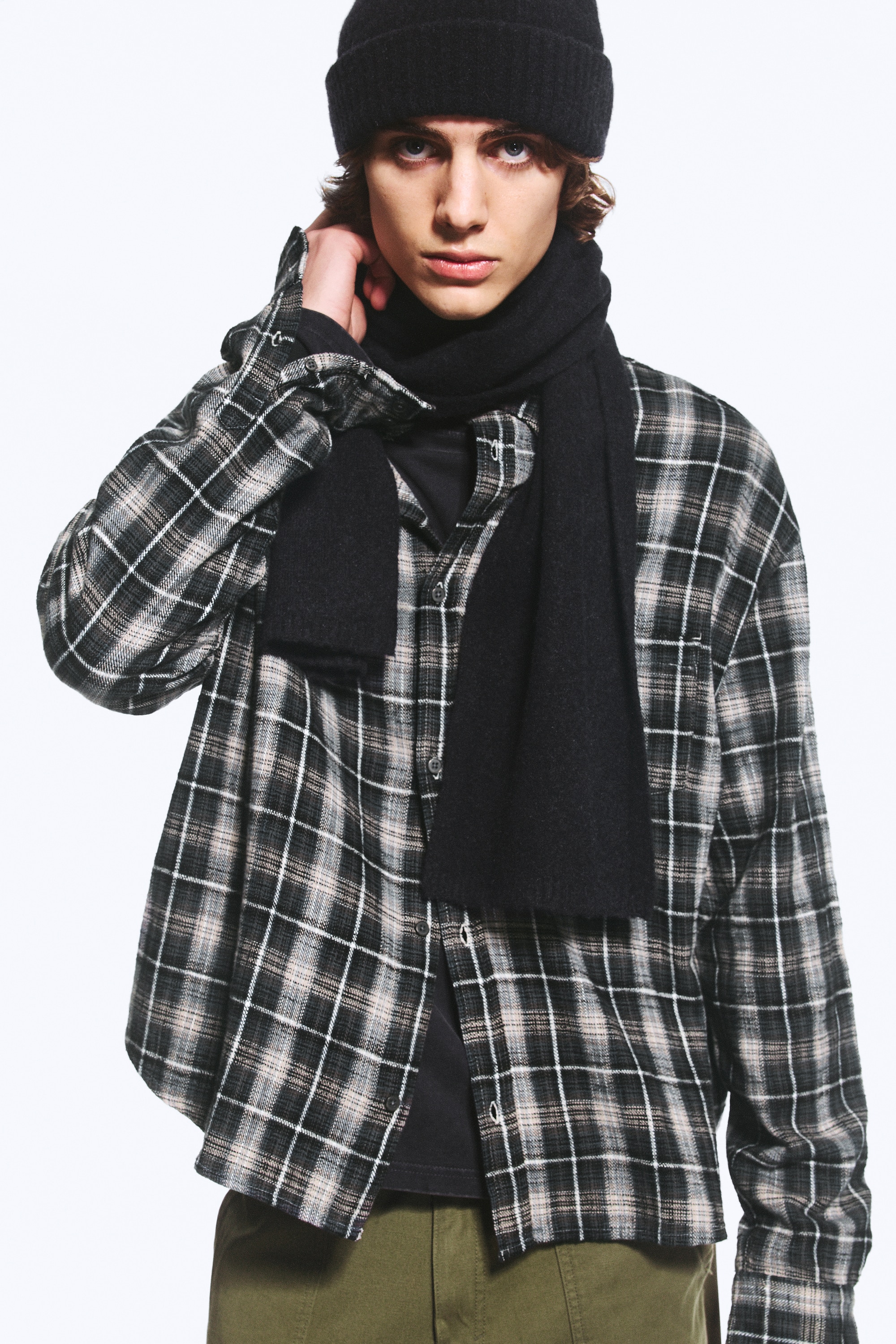 A dark navy plain-knit wool-blend scarf is draped in a loose loop at the front, showing its soft texture and clean, rectangular edges.