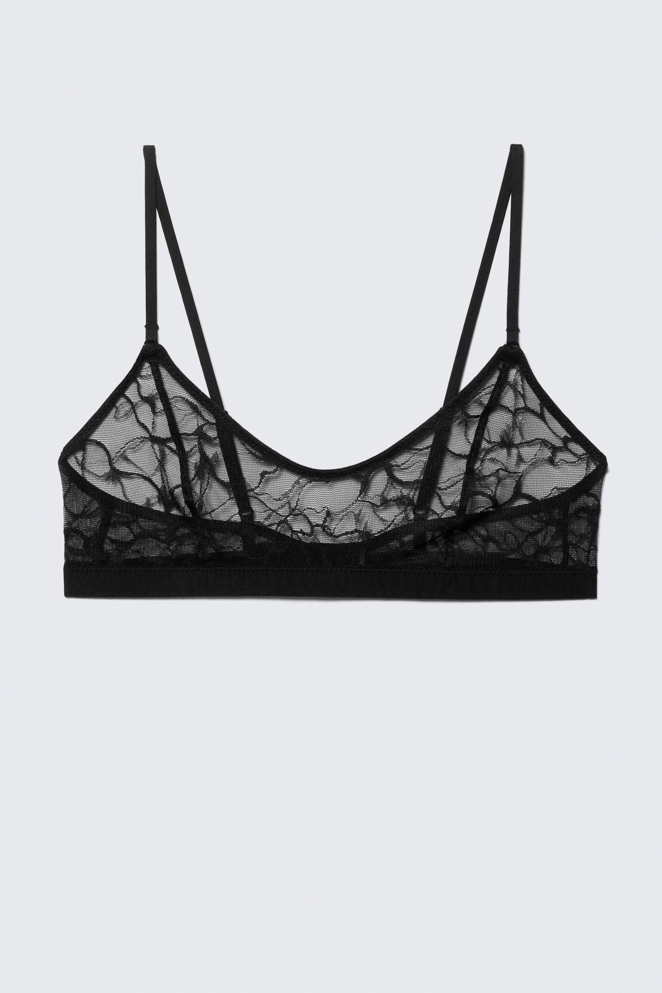 Agrandir l'image: Un bralette noir est présenté de face. Il est doté de bonnets en dentelle florale transparente, de fines bretelles ajustables et d'une bande élastique étroite qui constitue le bas.