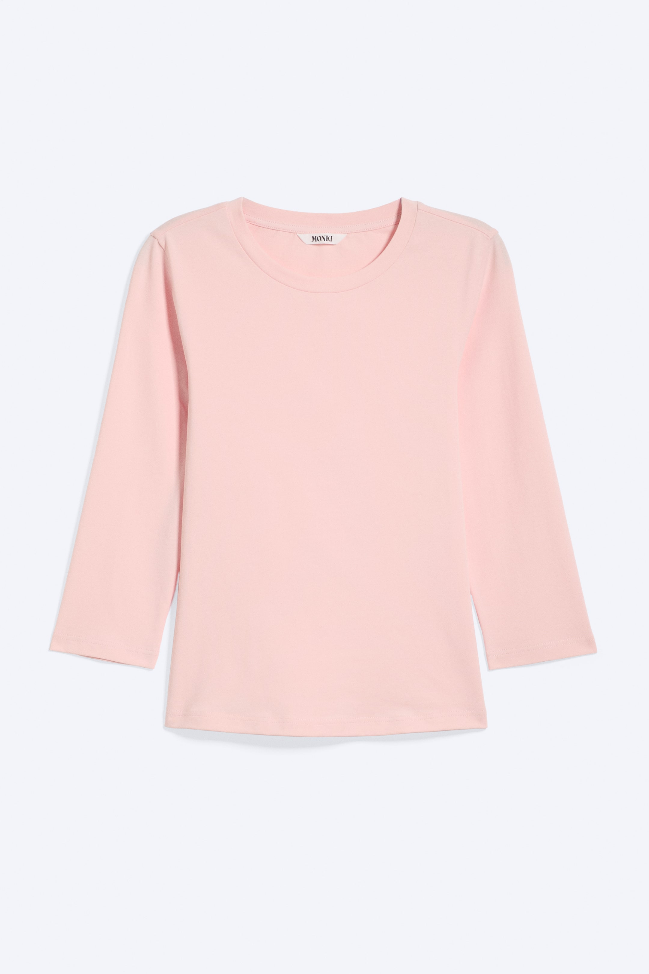 Se større billede: En lyserød top præsenteres fra forsiden, med rund halsudskæring og trekvartlange ærmer. Et lille hvidt "MONKI"-mærke er synligt bag på halsen, og toppen er designet med en lige kant.