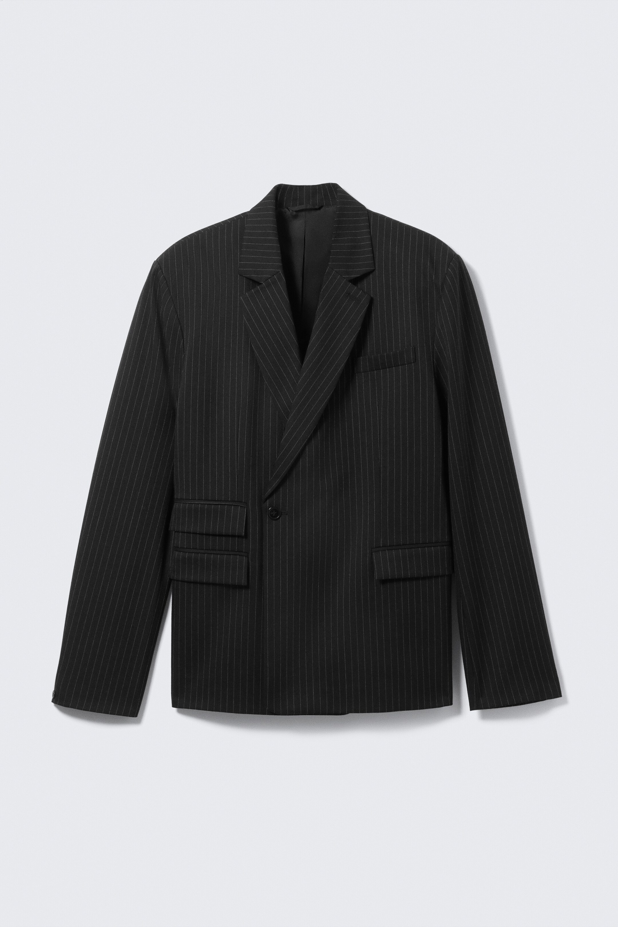 Größeres Bild ansehen: Ein schwarzer zweireihiger Blazer ist von vorne zu sehen und zeigt weiße Nadelstreifen. Er verfügt über Kerbrevers, einen sichtbaren Knopfverschluss, eine Leistentasche auf der Brust und zwei Pattentaschen.