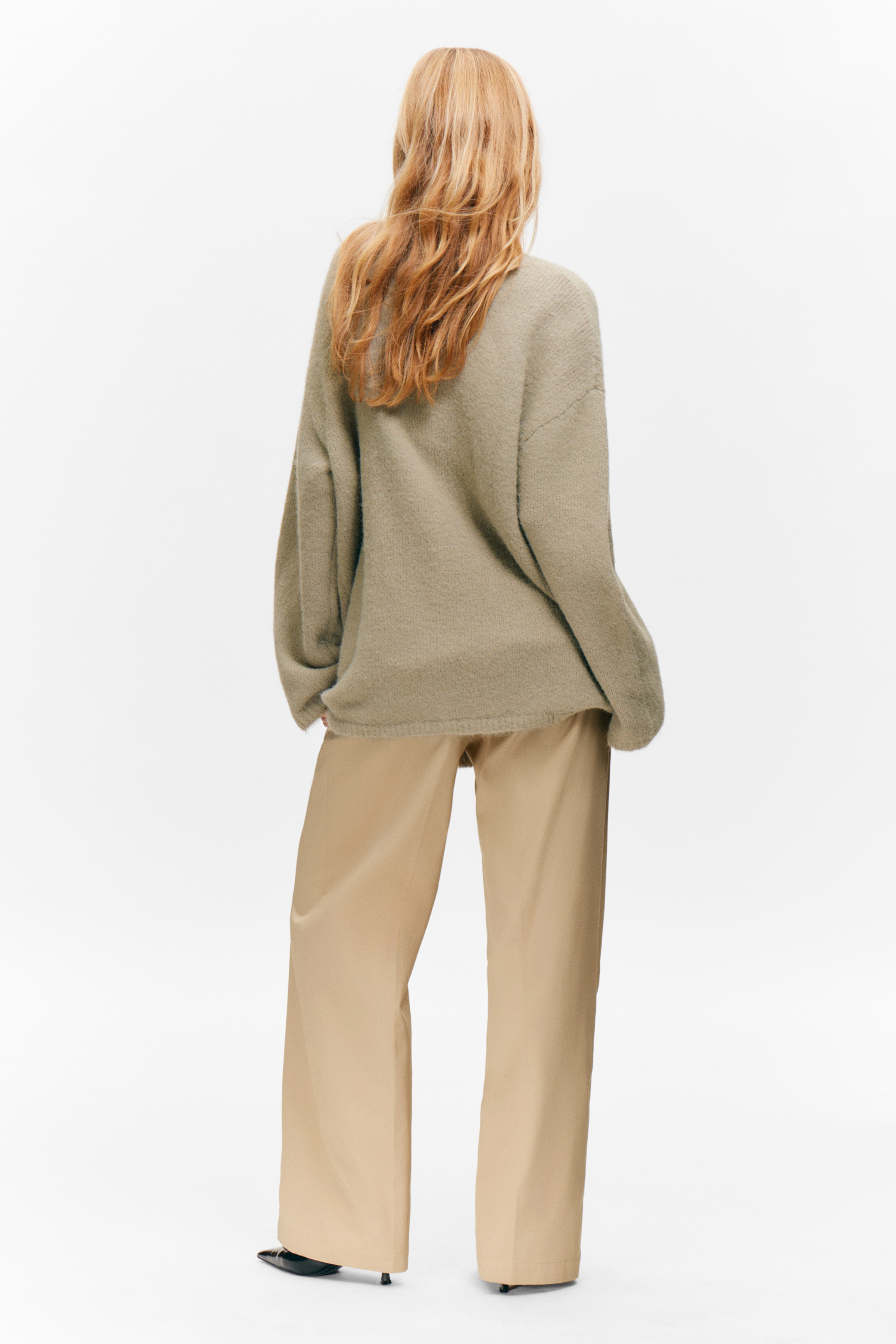 Ingrandisci l'immagine: Un maglione a maglia oversize verde spento è mostrato dal retro, con spalle cadenti e una vestibilità rilassata. È indossato sopra pantaloni color cachi a gamba larga e a lunghezza intera con una finitura liscia.