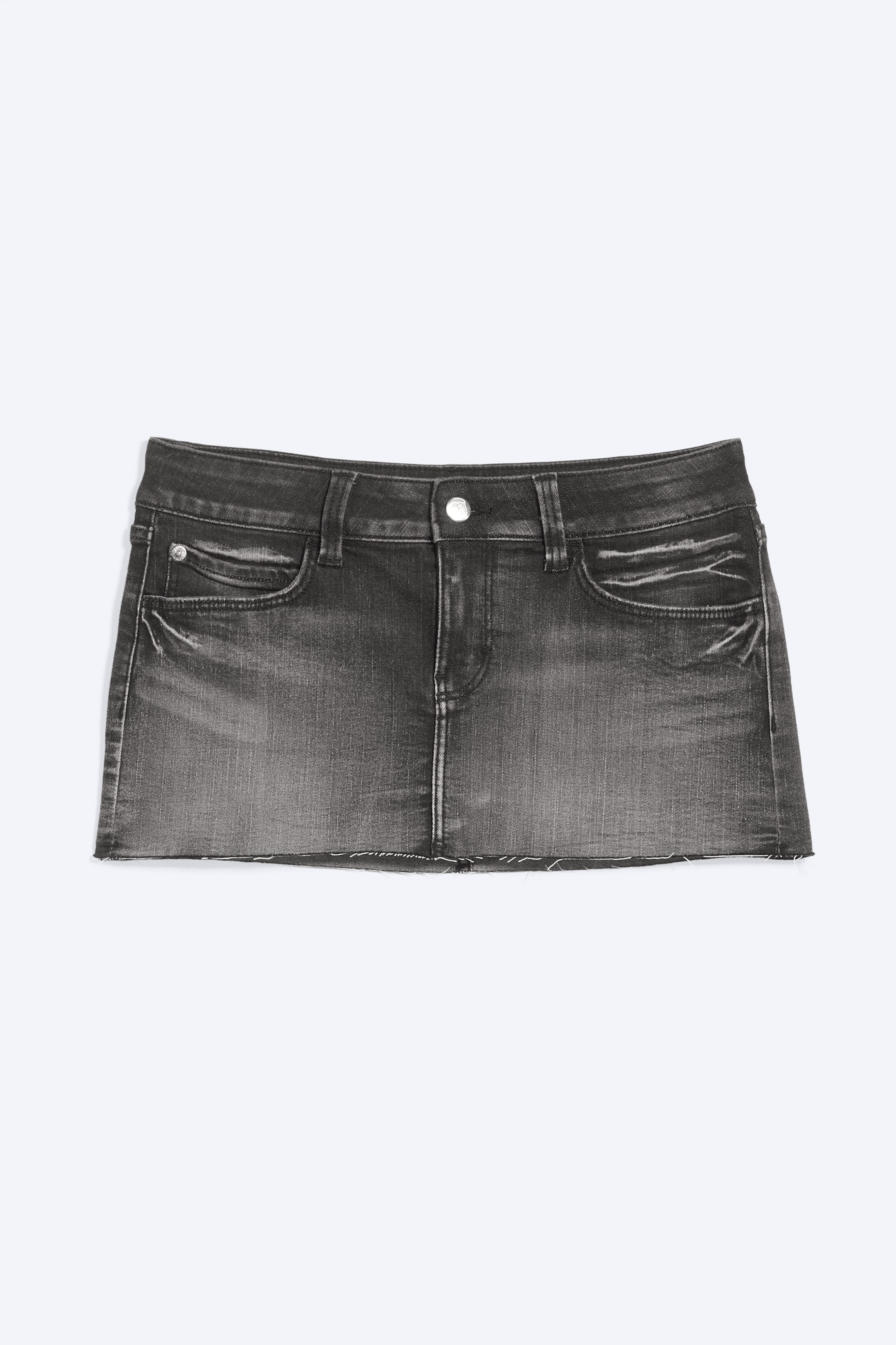 Visa större bild: En tvättad svart denim minikjol visar en framknäppning med knappar och dragkedja, bälteshällor och två böjda framfickor, inklusive en liten myntficka. Den har en blekt tvätt med whiskering på låren och en rå, ofärdig fåll.