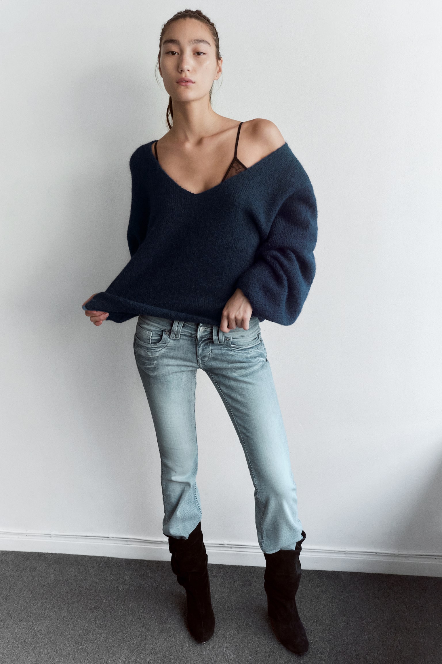 A navy blue knitted jumper is shown from the front, featuring a deep V-neckline and long, voluminous balloon sleeves. The garment is displayed in a soft, textured bouclé knit with a relaxed silhouette and a straight hem. - 1