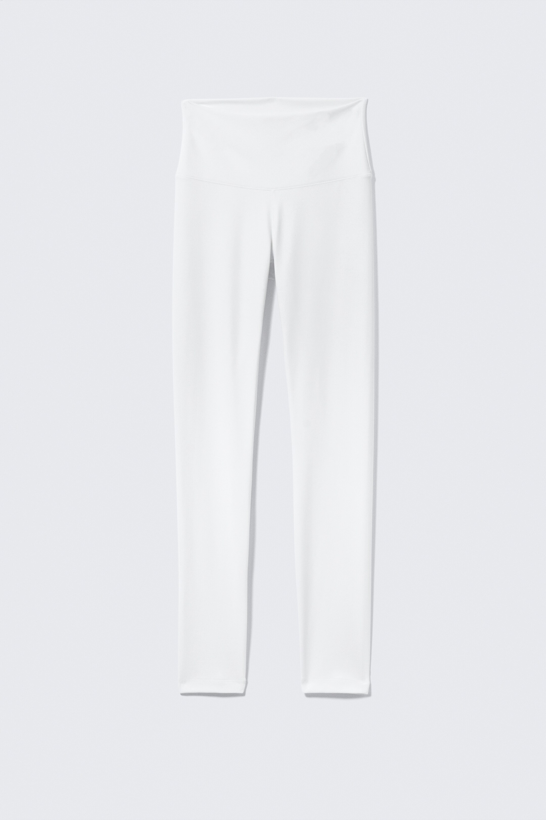 Agrandir l'image: Une paire de leggings blancs taille haute est présentée de face, avec une large ceinture et un design lisse et ajusté qui s'étend jusqu'aux chevilles.