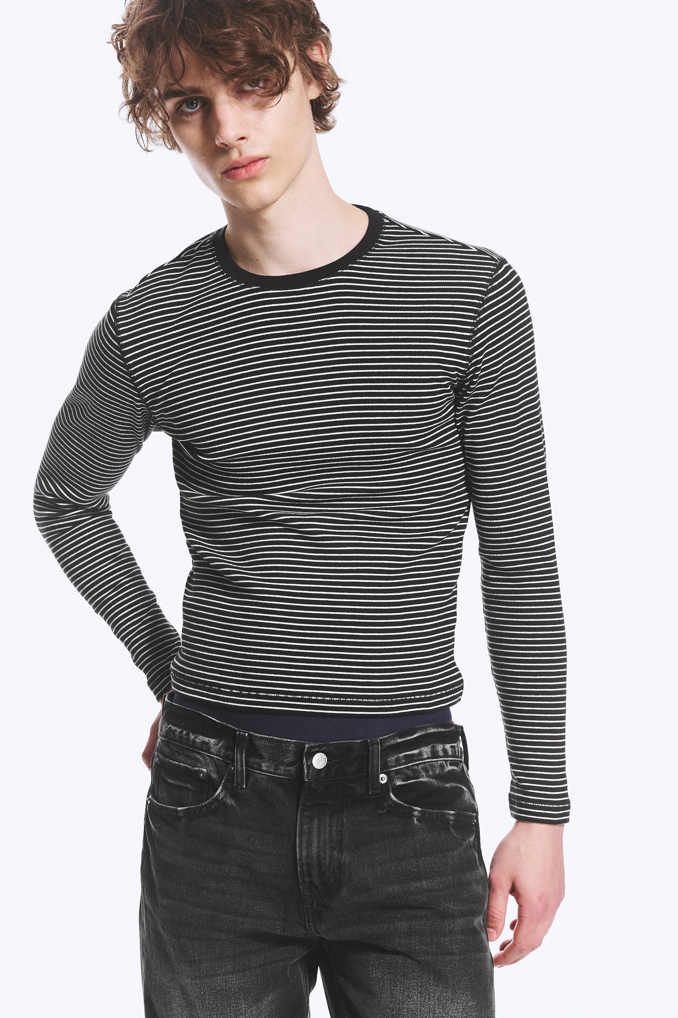 View larger image: A long-sleeved top featuring horizontal black and white stripes, a black crew neck, and a form-fitting design, with its hem tucked in.