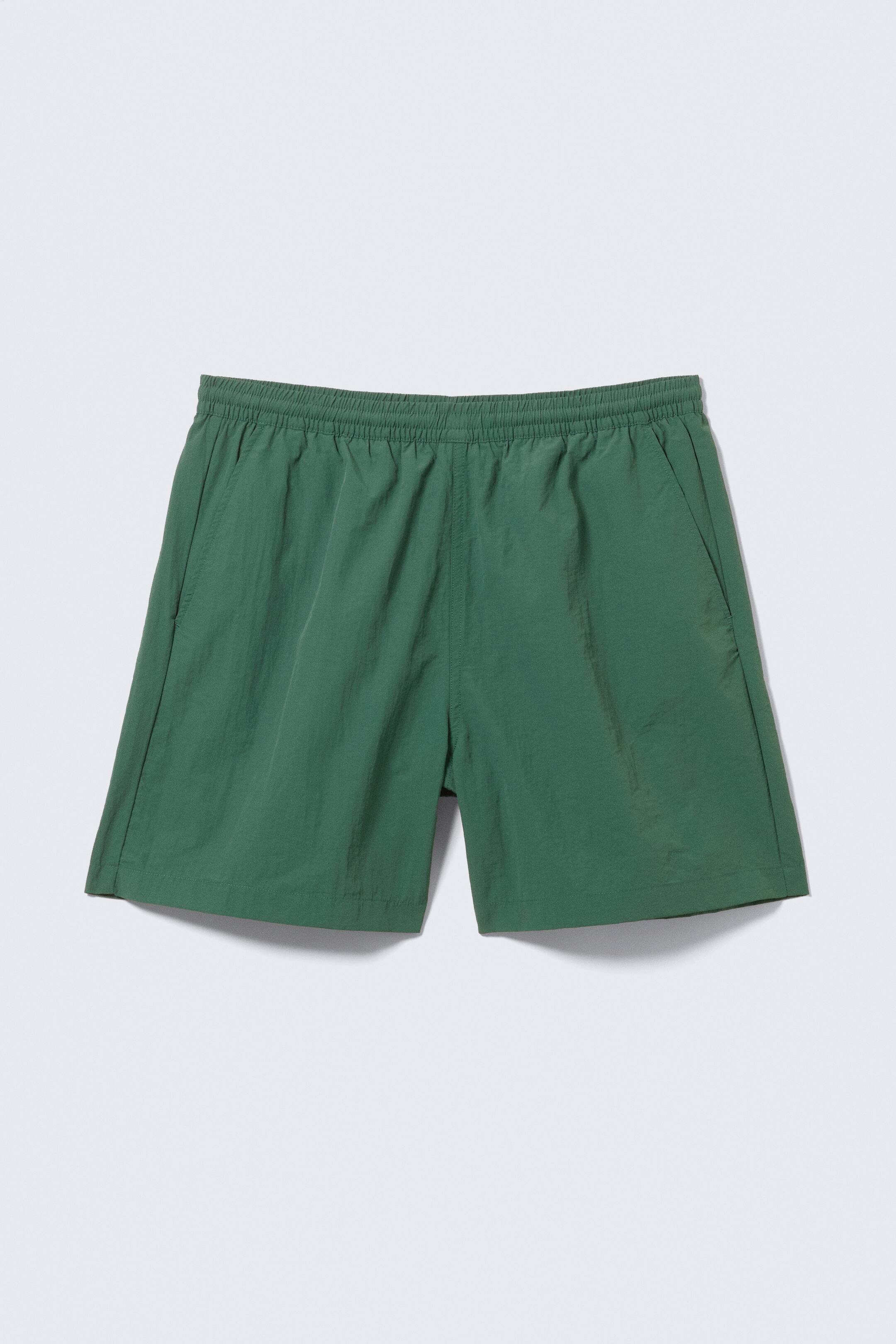 Agrandir l'image: Shorts verts présentés de face, dotés d'une taille élastiquée et de poches fendues sur les côtés.