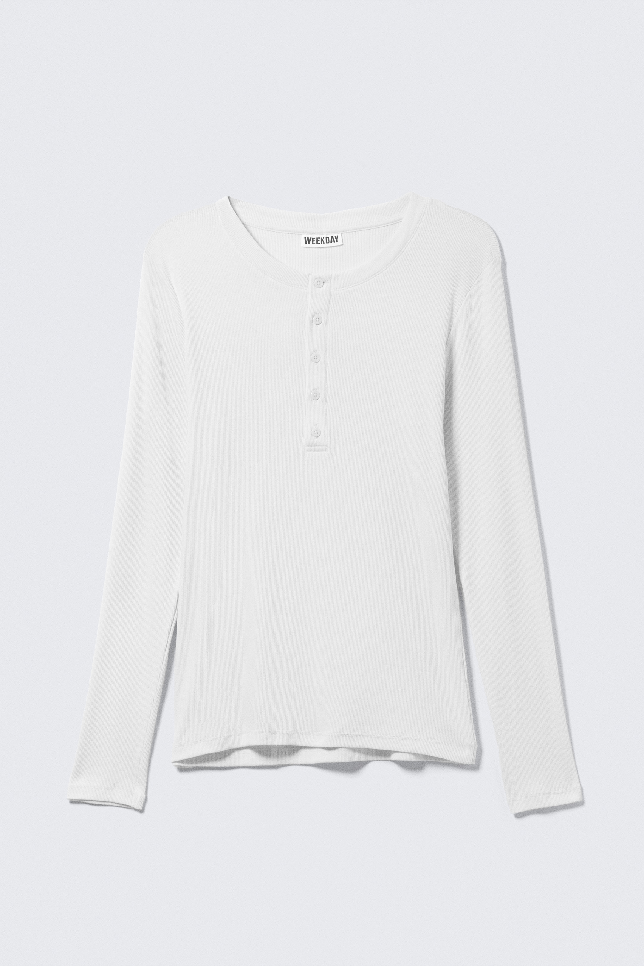 Agrandir l'image: Un t-shirt Henley blanc à manches longues est présenté à plat, orienté vers l'avant. Le t-shirt présente un tissu en maille côtelée, un col rond et une patte de boutonnage à cinq boutons.