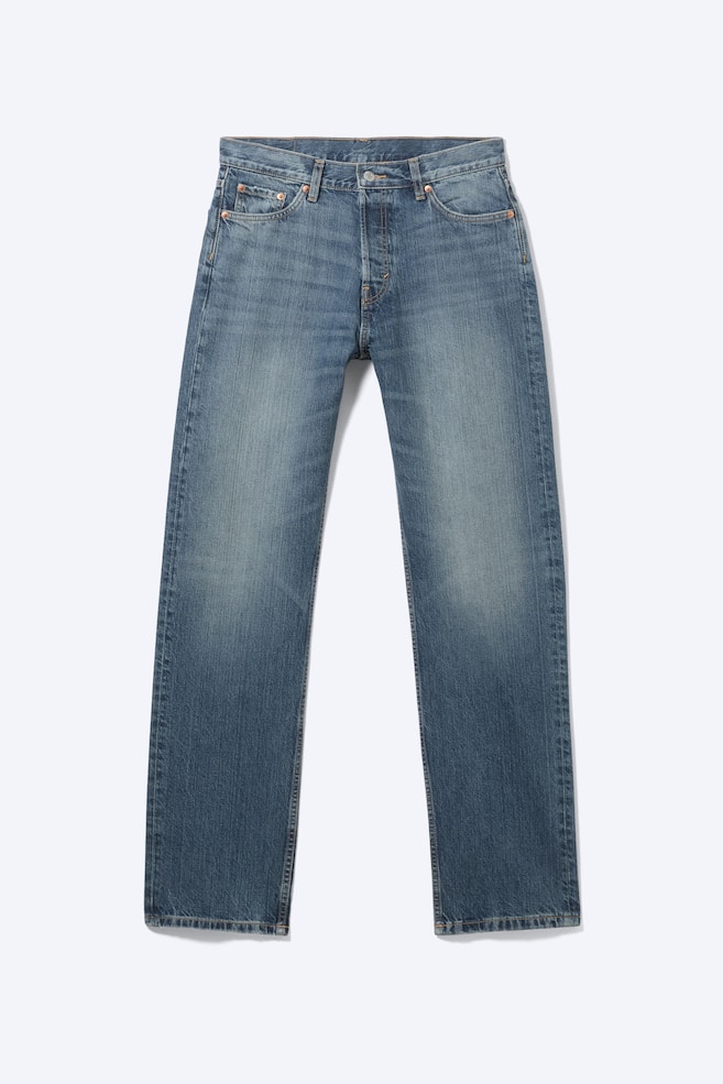 Un jean à taille mi-haute se présente à l'avant, avec une coupe décontractée et une jambe droite dans un délavage en denim bleu délavé. Il affiche un design classique à cinq poches et une braguette à boutons. - 1