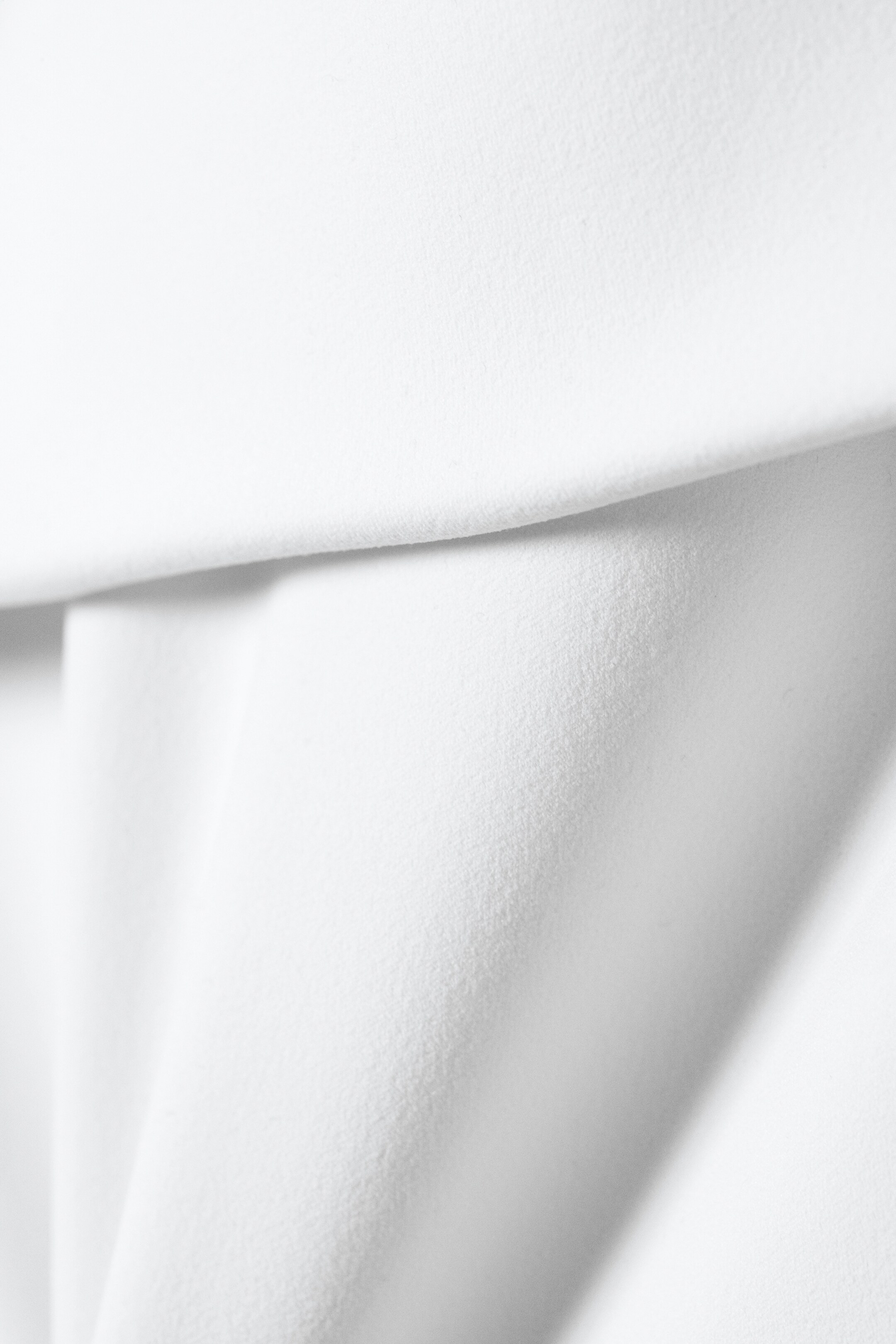 Agrandir l'image: Le tissu blanc présente des plis doux et une texture subtile.