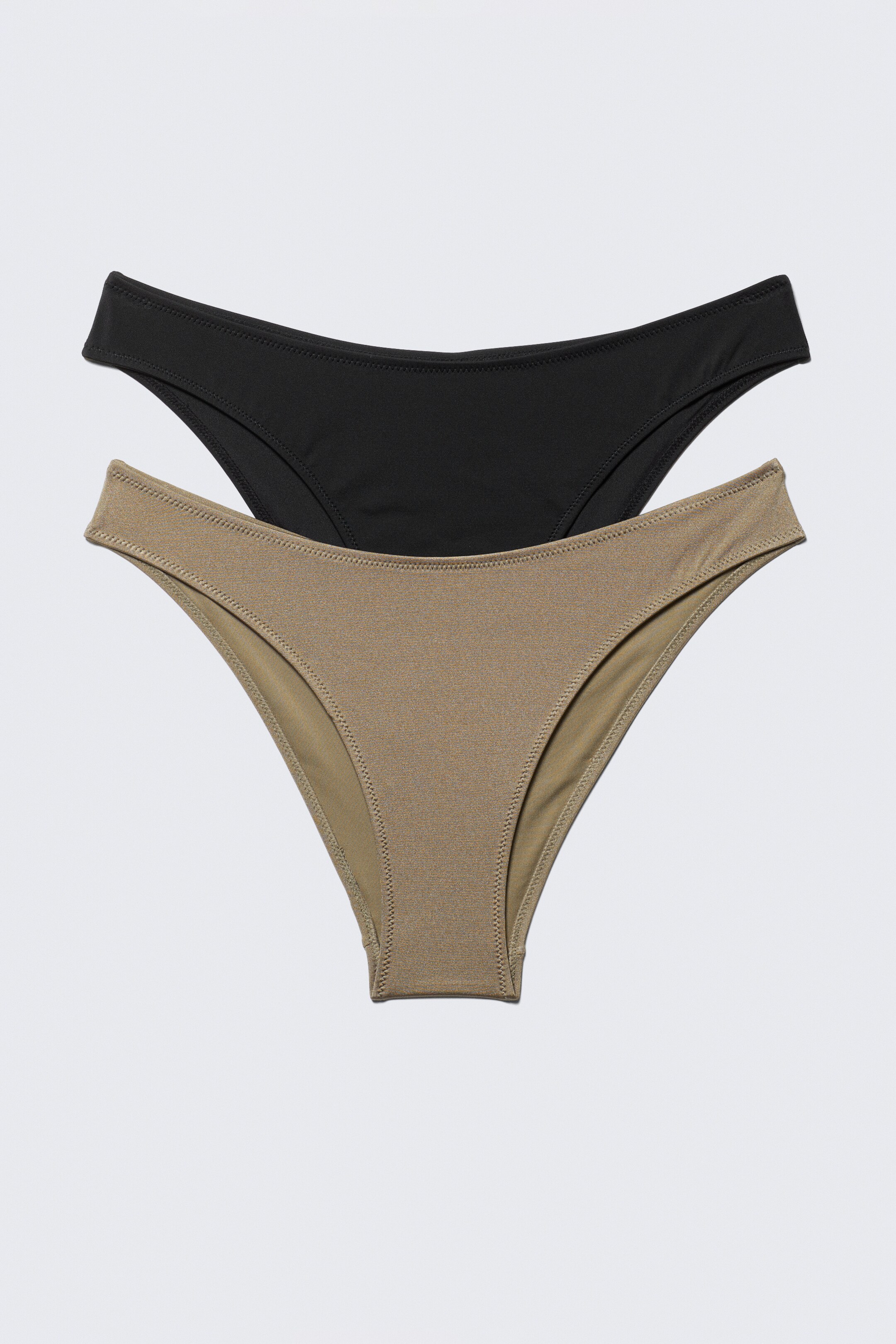 Vis større bilde: En 2-pakning med bikinibunn vises i en FORAN-visning, med en svart og en khaki bunn. Begge bunnene er designet med minimal dekning, et høyt snitt og en litt buet midje.