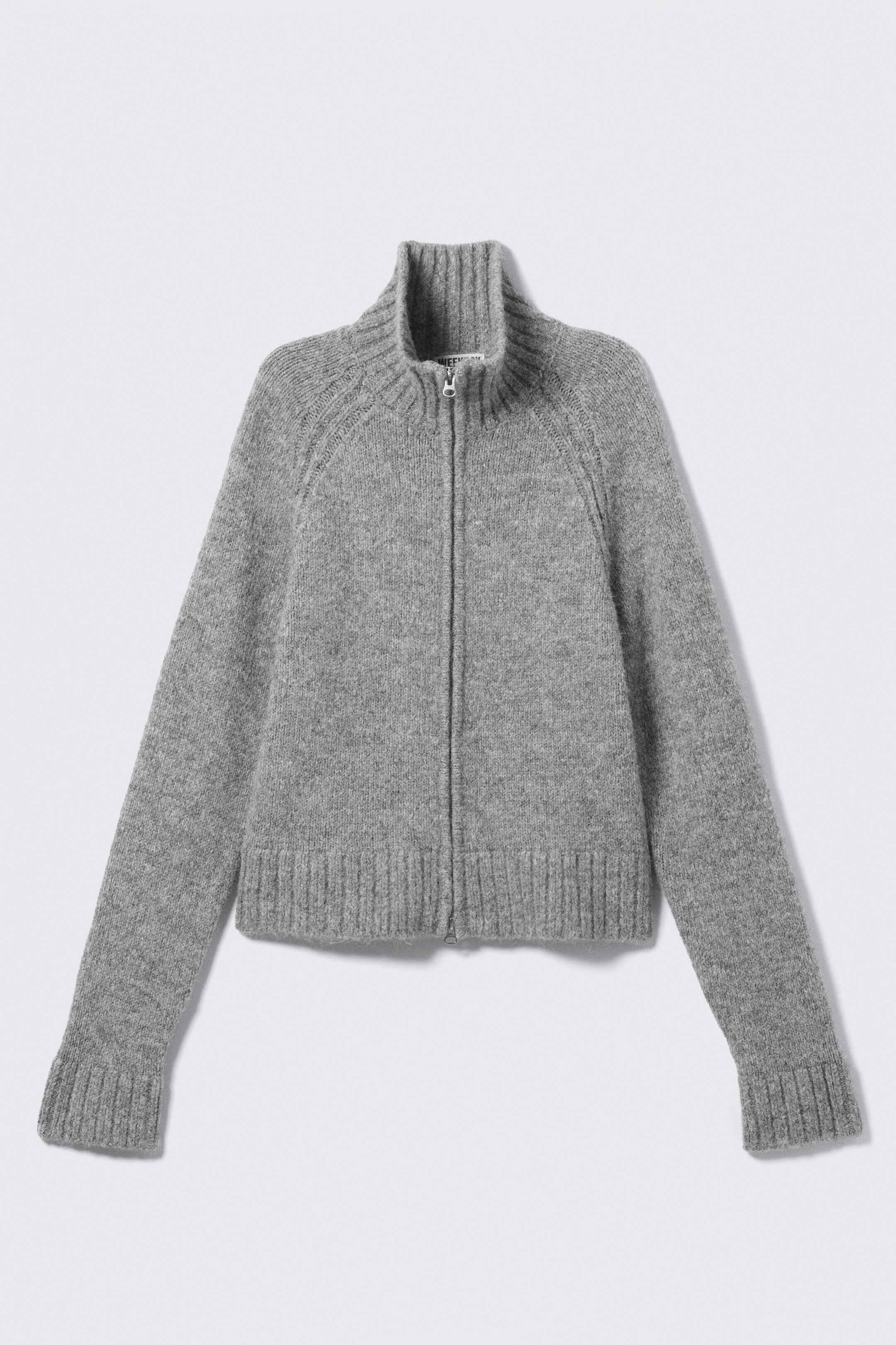 Größeres Bild ansehen: Ein grauer, schmal geschnittener Reißverschluss-Cardigan, gestrickt aus einem strukturierten Garn, wird VORNE präsentiert und zeichnet sich durch Raglanärmel, einen hohen gerippten Kragen, einen Zwei-Wege-Reißverschluss, breite gerippte Bündchen und komplett ausgestattete Details aus.