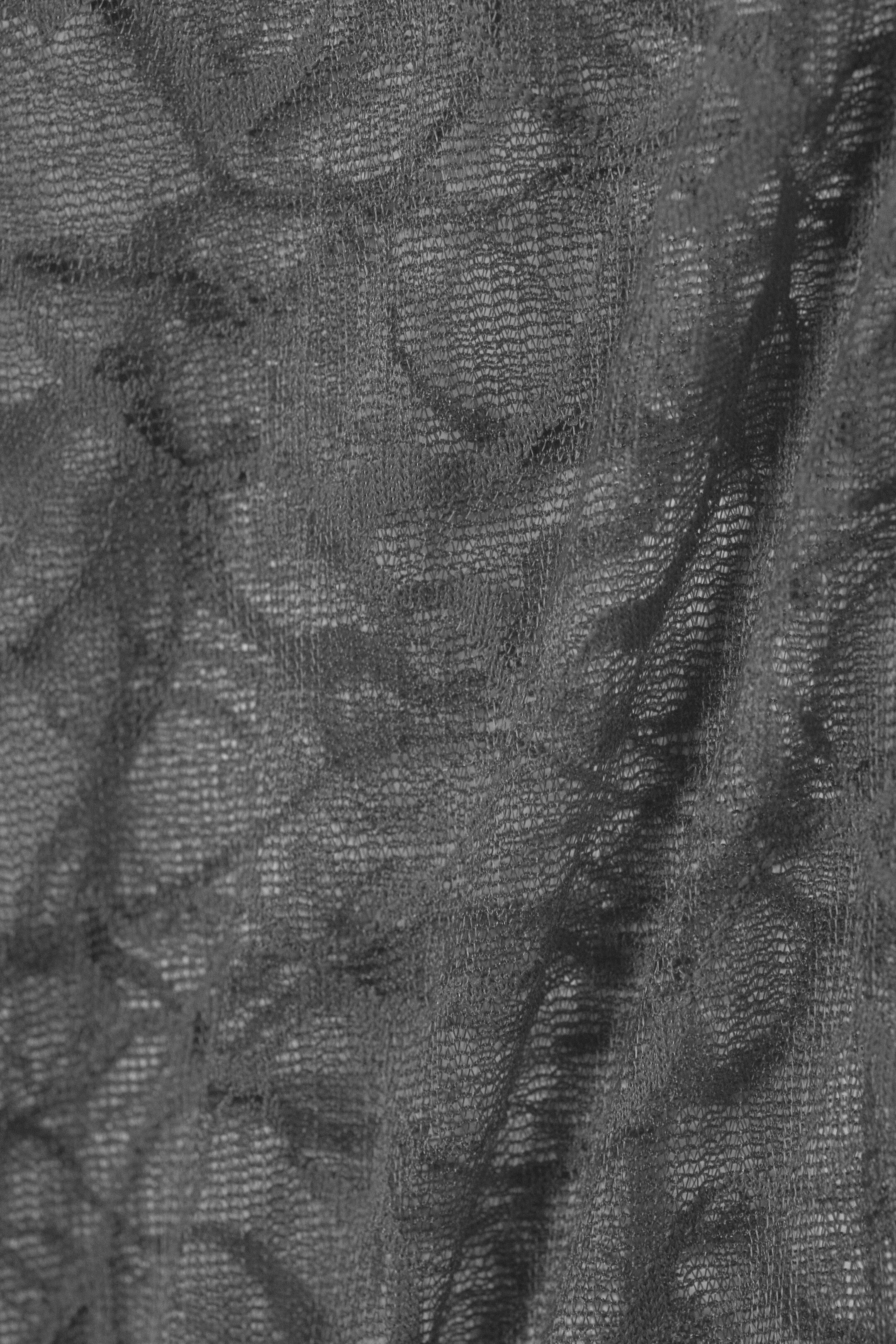Agrandir l'image: Un tissu gris foncé à tissage ouvert présente une texture irrégulière et froissée sur toute sa surface.