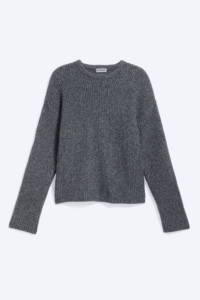 Un jersey melange gris oscuro estÃ¡ orientado hacia el frente, con un corte relajado, escote redondo y hombros caÃ­dos. Presenta una confecciÃ³n de punto grueso texturizado con mangas largas que terminan en puÃ±os ligeramente holgados. - 1