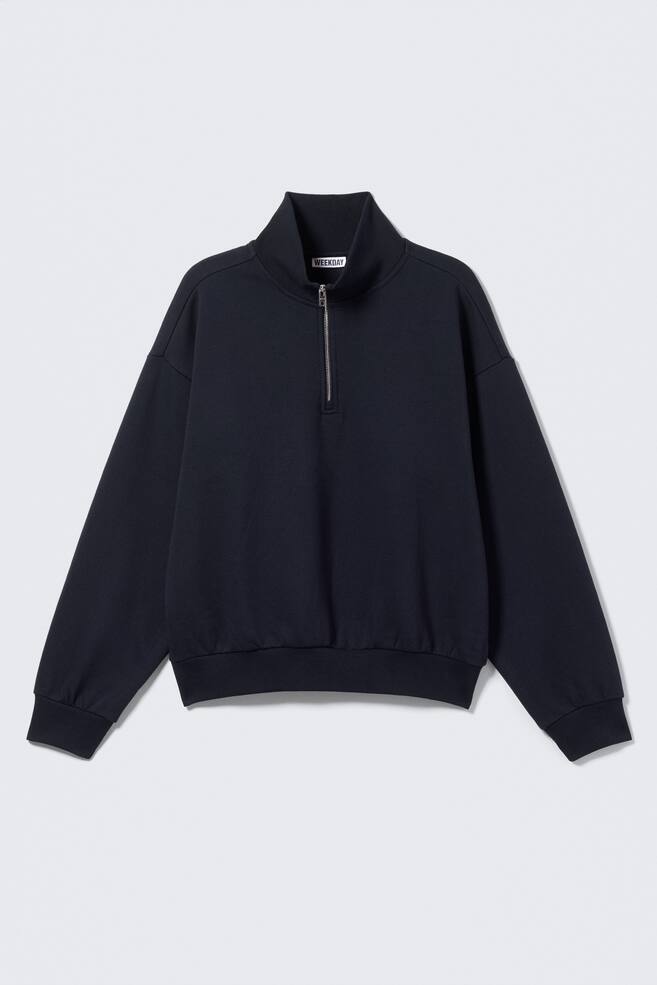 A dark blue sweatshirt is shown from a front view, featuring a high stand-up collar with a silver-toned half-zip closure. It has dropped shoulders, long sleeves with ribbed cuffs, and a ribbed hem. - 1