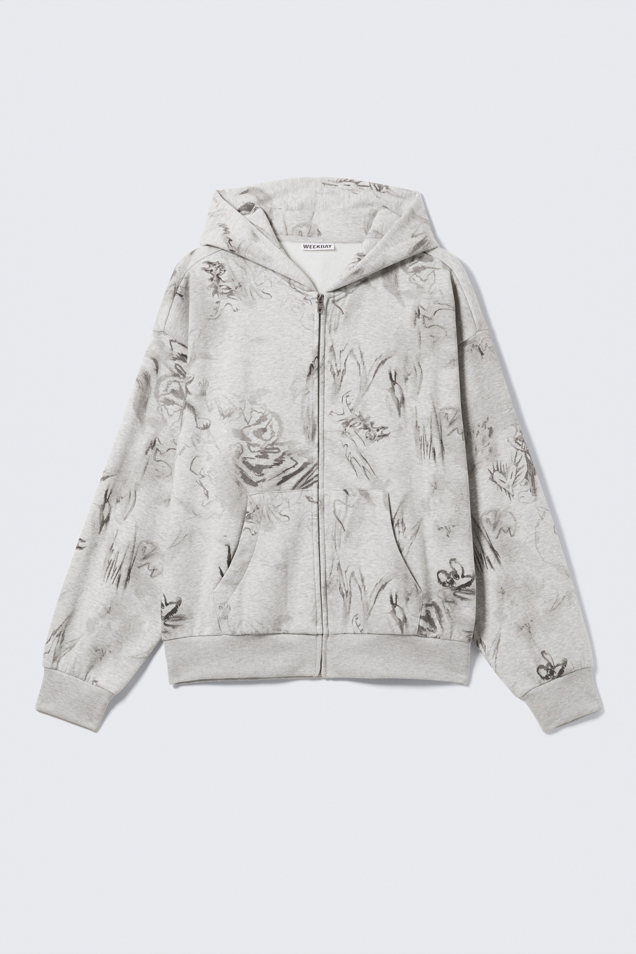 Visa större bild: En ljusgrå zip-hoodie med ett abstrakt mörkgrått mönster presenteras framifrån, vilket visar dess avslappnade, fyrkantiga passform. Den har en dubbellager huva, en synlig metallblixtlås framtill, nedhasade axlar, kängurufickor och ribbade muddar och fåll.