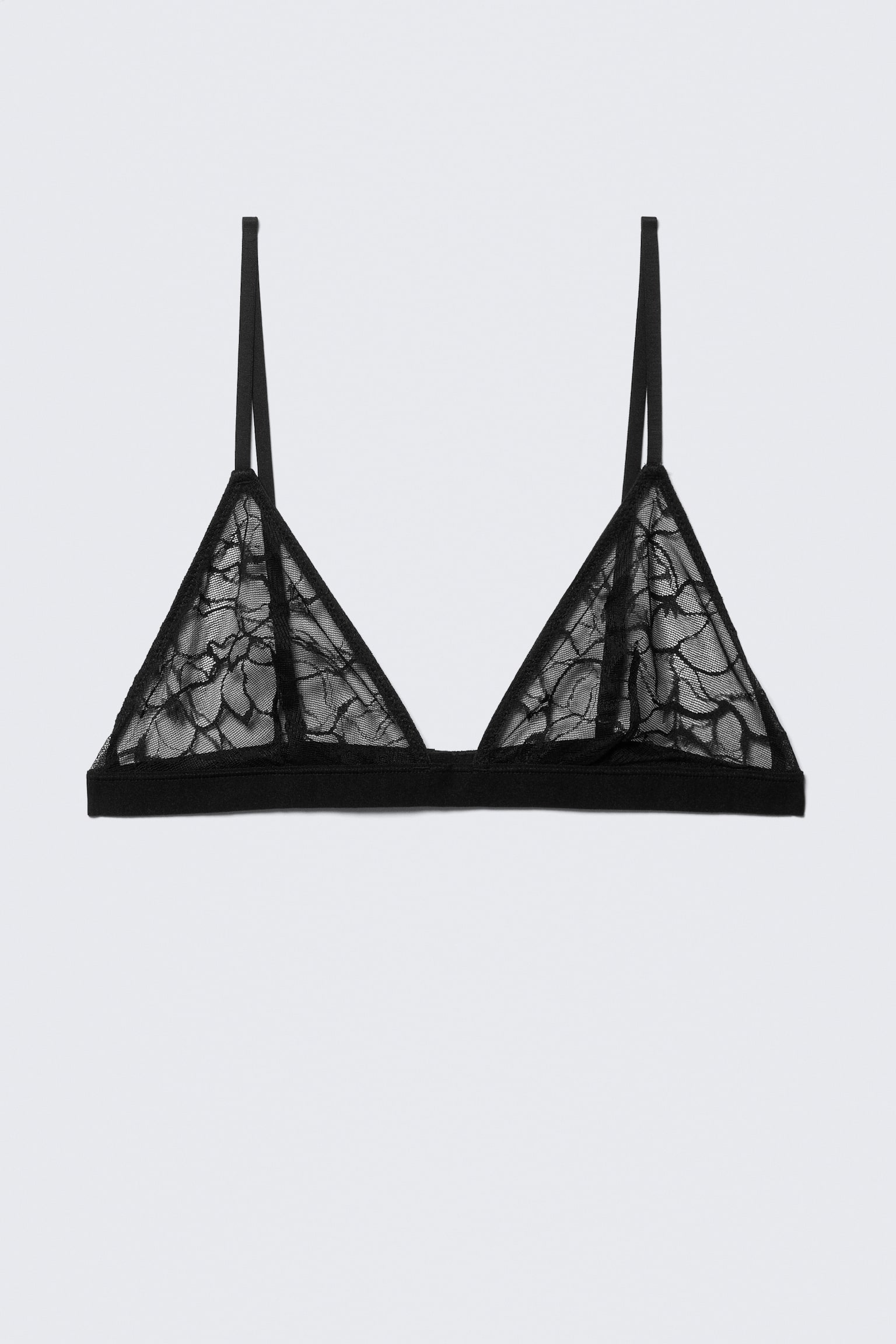 Un triangolo bralette in pizzo nero presenta coppe trasparenti con un intricato motivo floreale. Sottili spalline si attaccano alla parte superiore delle coppe, e una fascia elastica solida forma la base, presentata di fronte.