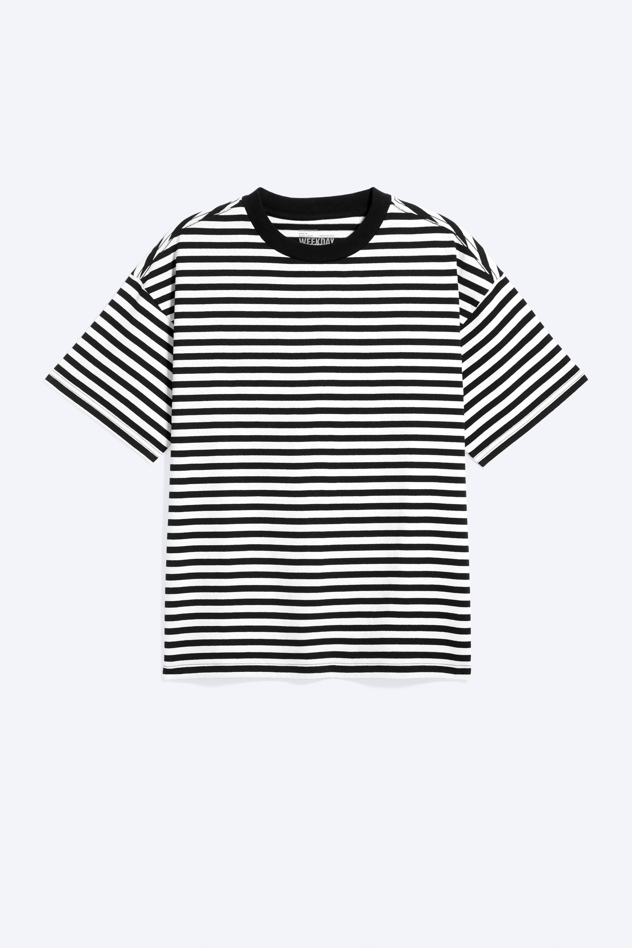 Agrandir l'image: Un T-shirt oversize est présenté de face, avec des rayures horizontales noires et blanches, un col rond côtelé noir, des épaules tombantes et des manches larges, pour une coupe ample.